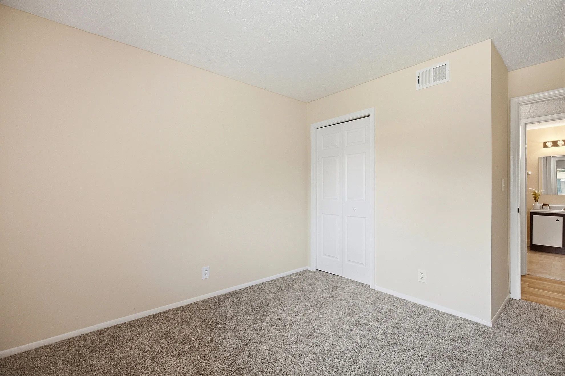 Bright and inviting bedroom featuring soft carpet floors, neutral walls, and a convenient closet.