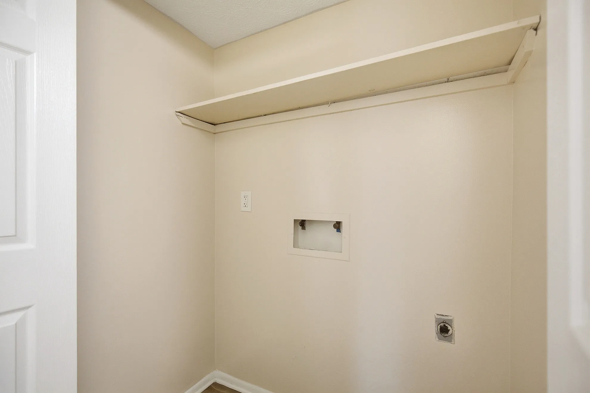 Bright and spacious laundry room with convenient shelving and hook-ups, ready for your washer and dryer.