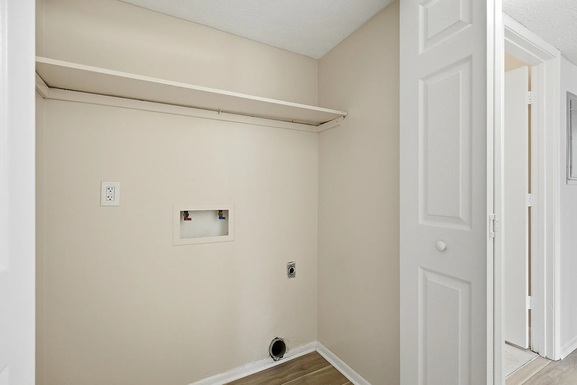 Bright and versatile laundry nook with built-in shelf, ready for washer and dryer installation, in a modern apartment.