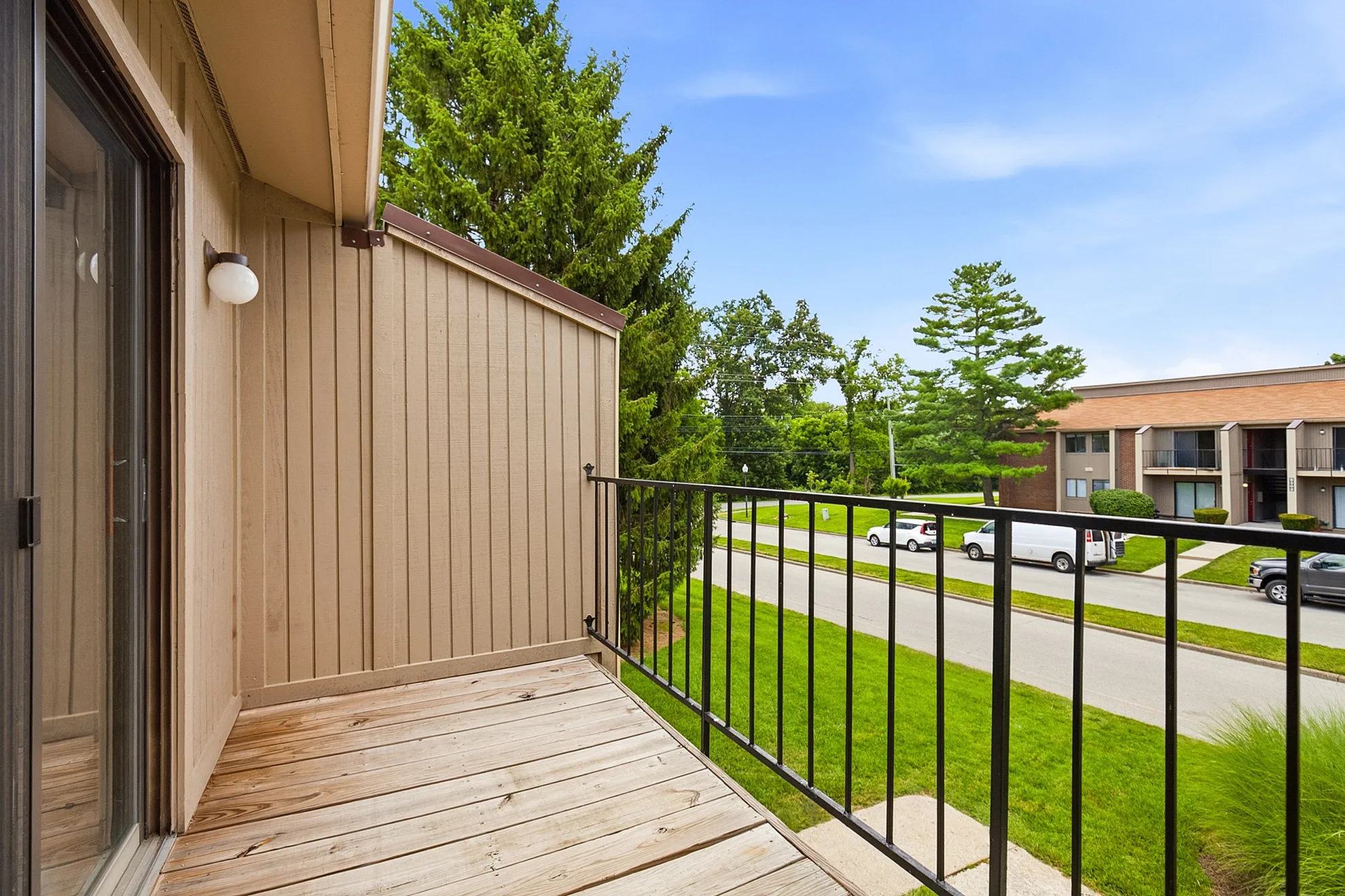 Charming balcony view over lush greenery and tranquil street, perfect for relaxation and enjoying the outdoors.