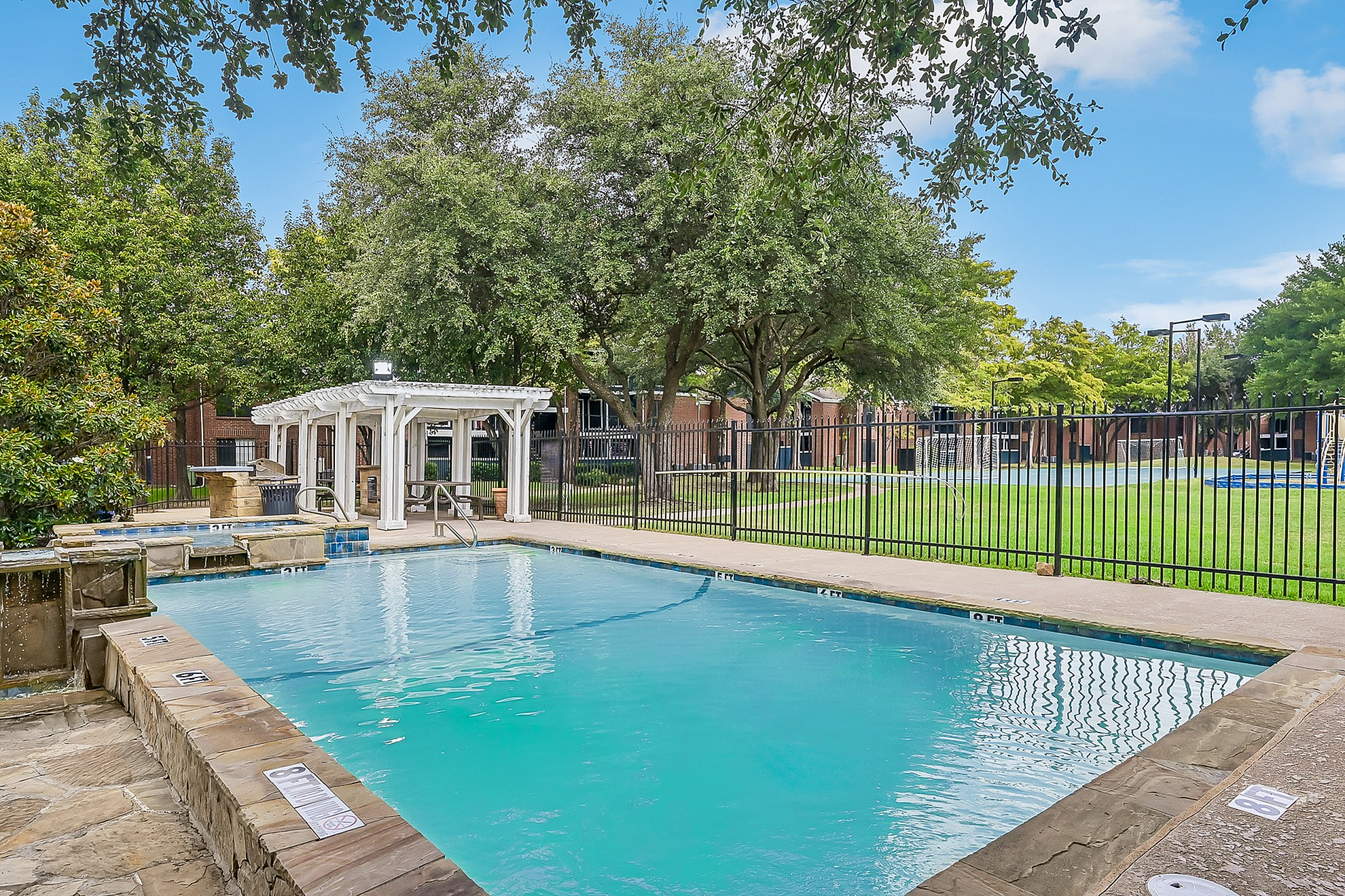 Inviting outdoor pool area with a stylish pergola and lush green surroundings, perfect for relaxation and entertaining.
