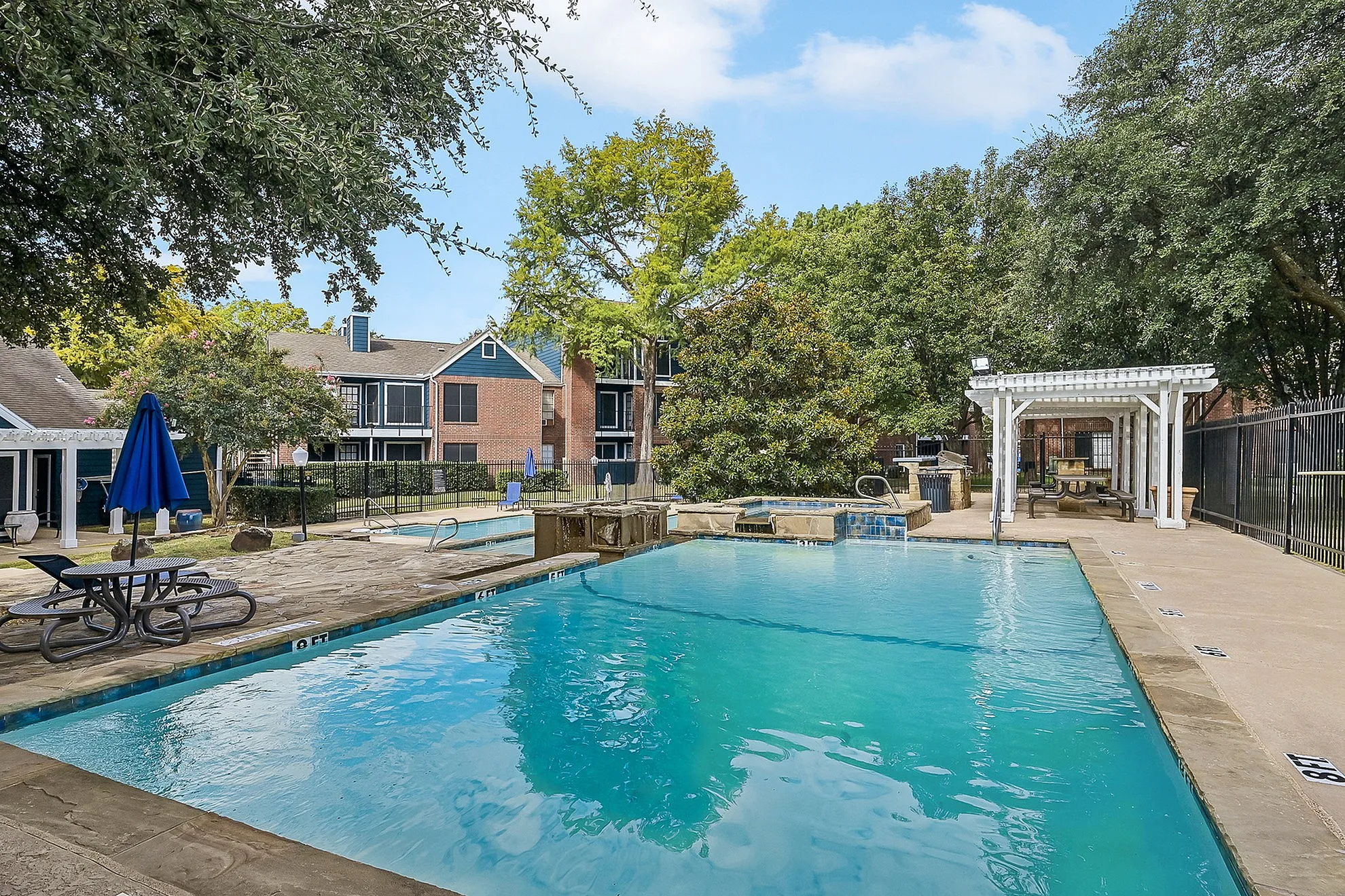 Inviting residential pool area with lush greenery, modern loungers, and a charming pergola, perfect for relaxation and social gatherings.
