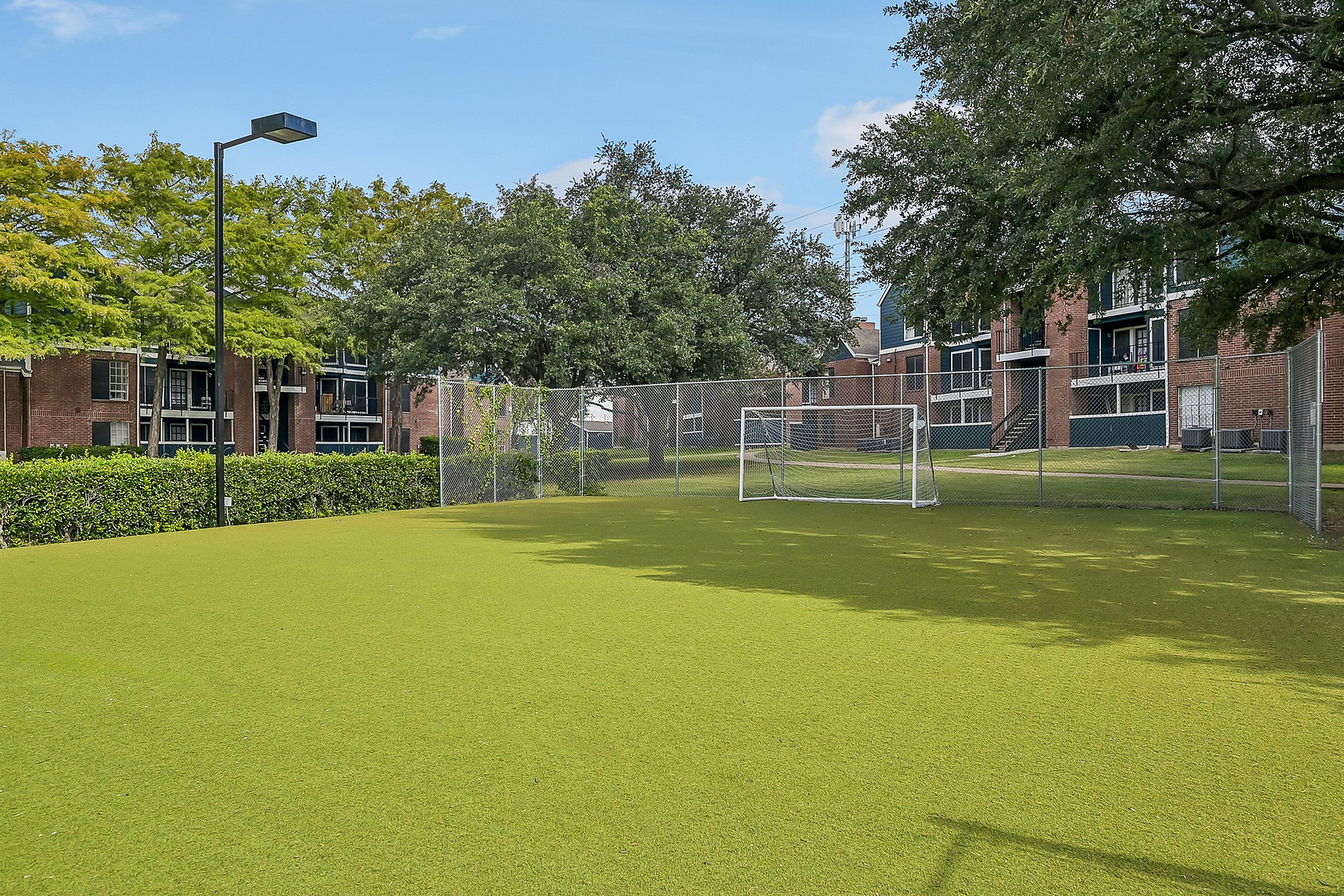 Vibrant outdoor soccer field surrounded by lush greenery and modern apartment buildings, ideal for active living.
