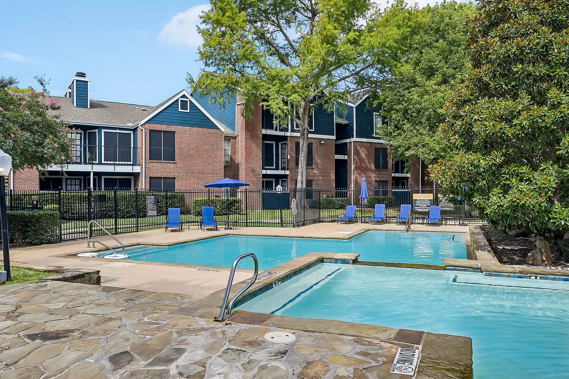 Inviting outdoor pool area with comfortable lounge chairs and vibrant greenery, enhancing a modern apartment complex.