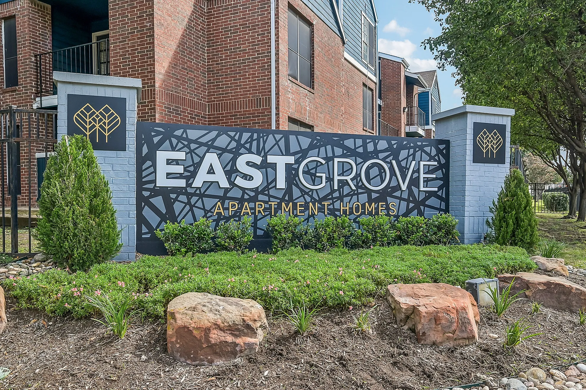 Charming EastGrove Apartment Homes entrance with lush greenery and modern signage.