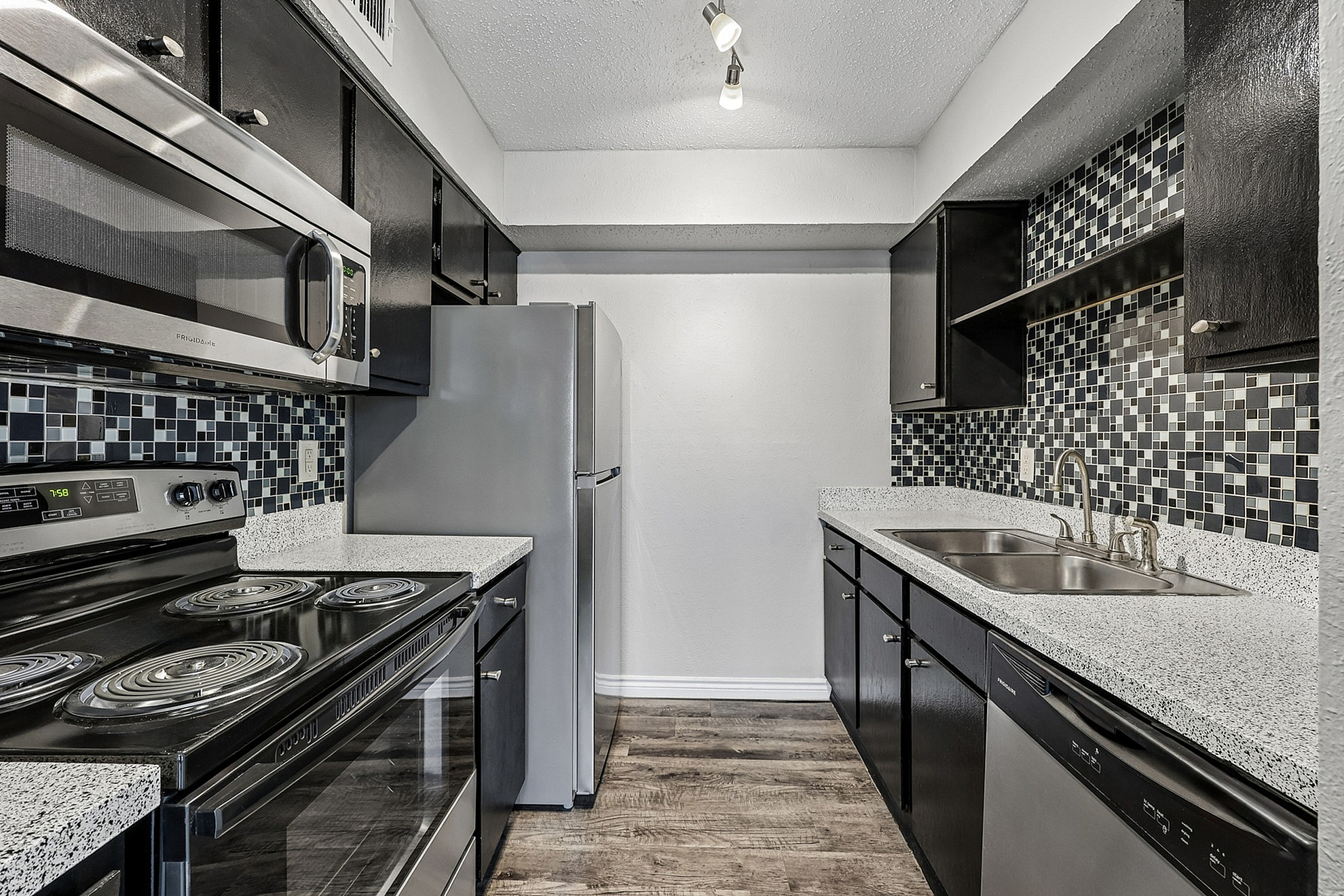 Modern kitchen with sleek stainless steel appliances, elegant black cabinetry, and stylish mosaic tile backsplash.