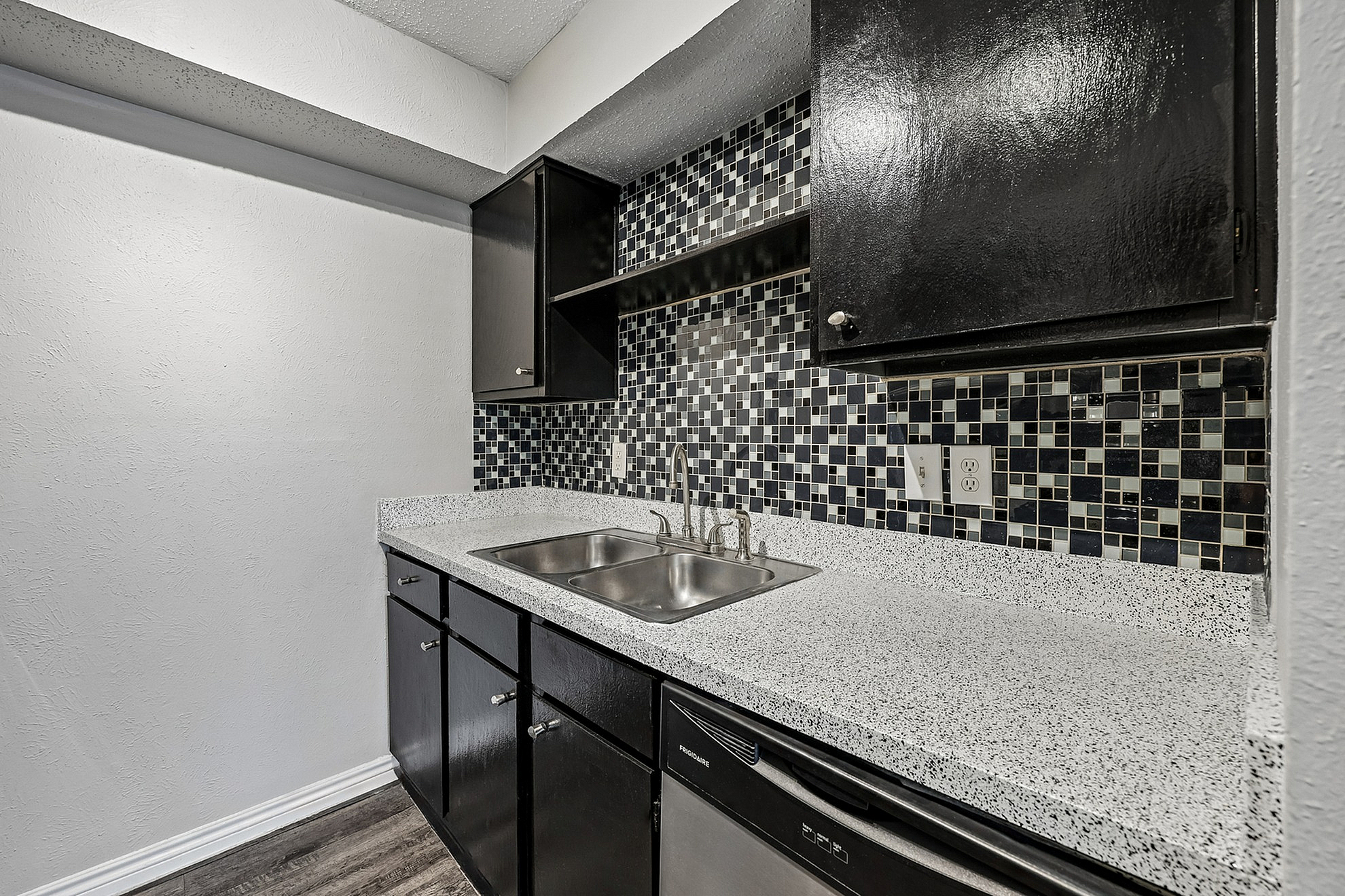 Modern kitchen with sleek black cabinetry, chic mosaic tile backsplash, and granite countertops.