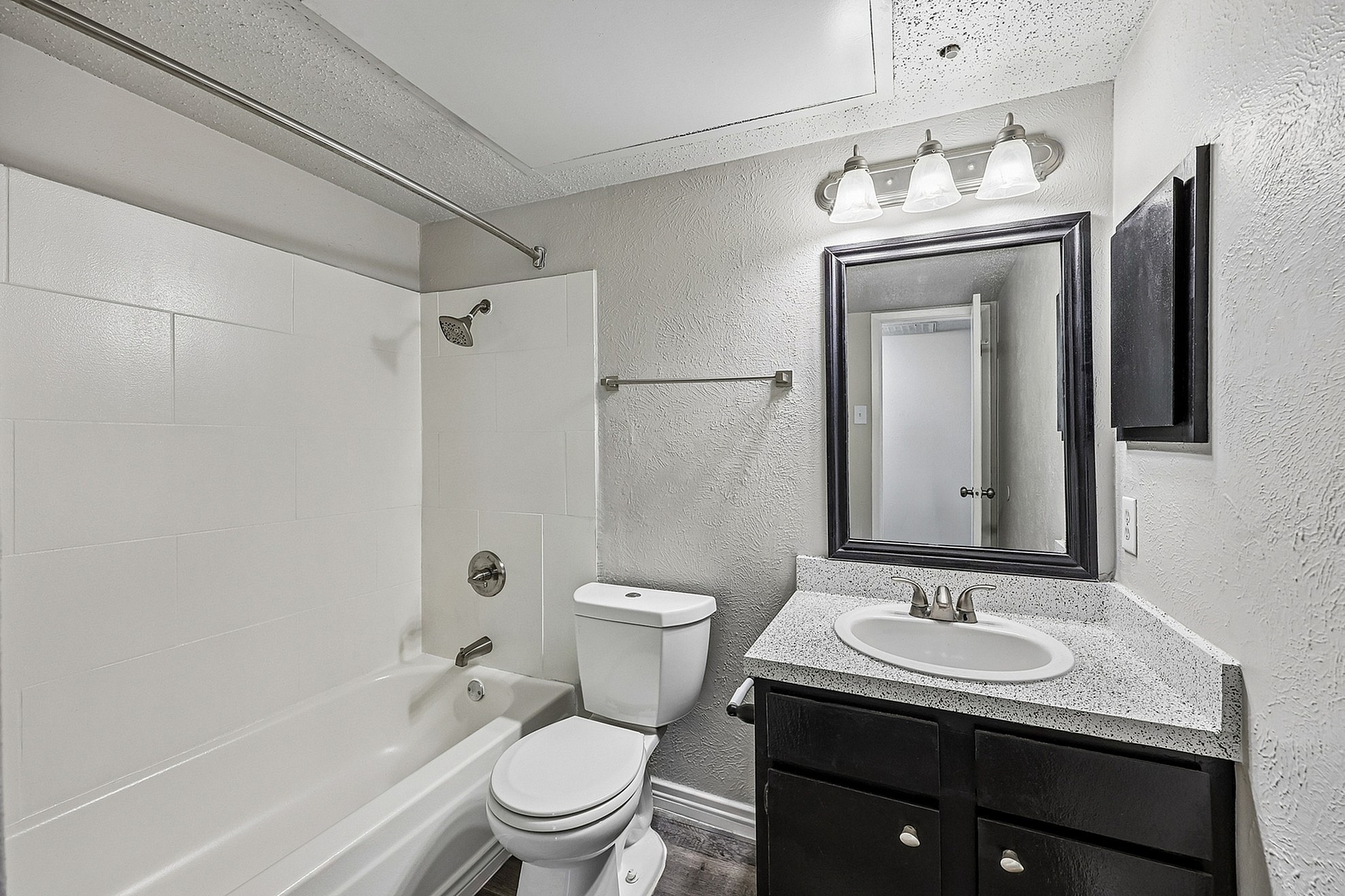 Modern bathroom with elegant lighting, sleek vanity, and a tiled shower-tub combination, showcasing contemporary design.