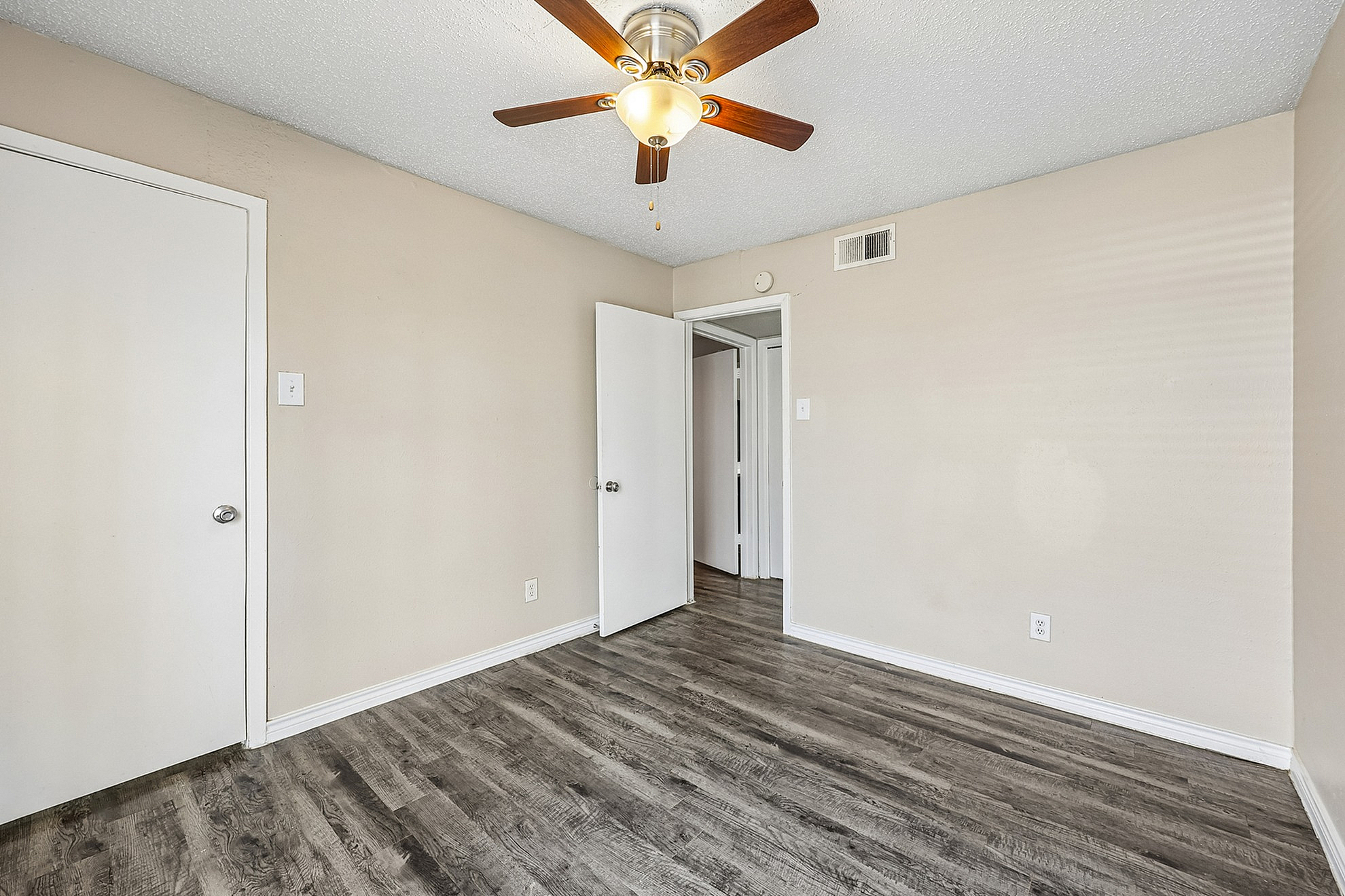 Charming room with elegant wood flooring, neutral walls, and modern ceiling fan for a cozy, stylish atmosphere.