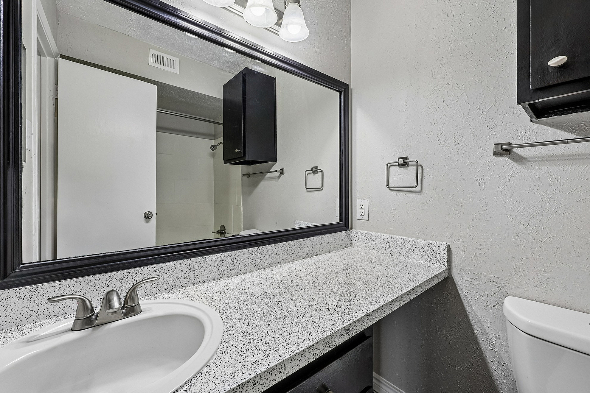 Modern bathroom showcasing a sleek granite countertop with a stylish sink and large mirror, accented by contemporary light fixtures.