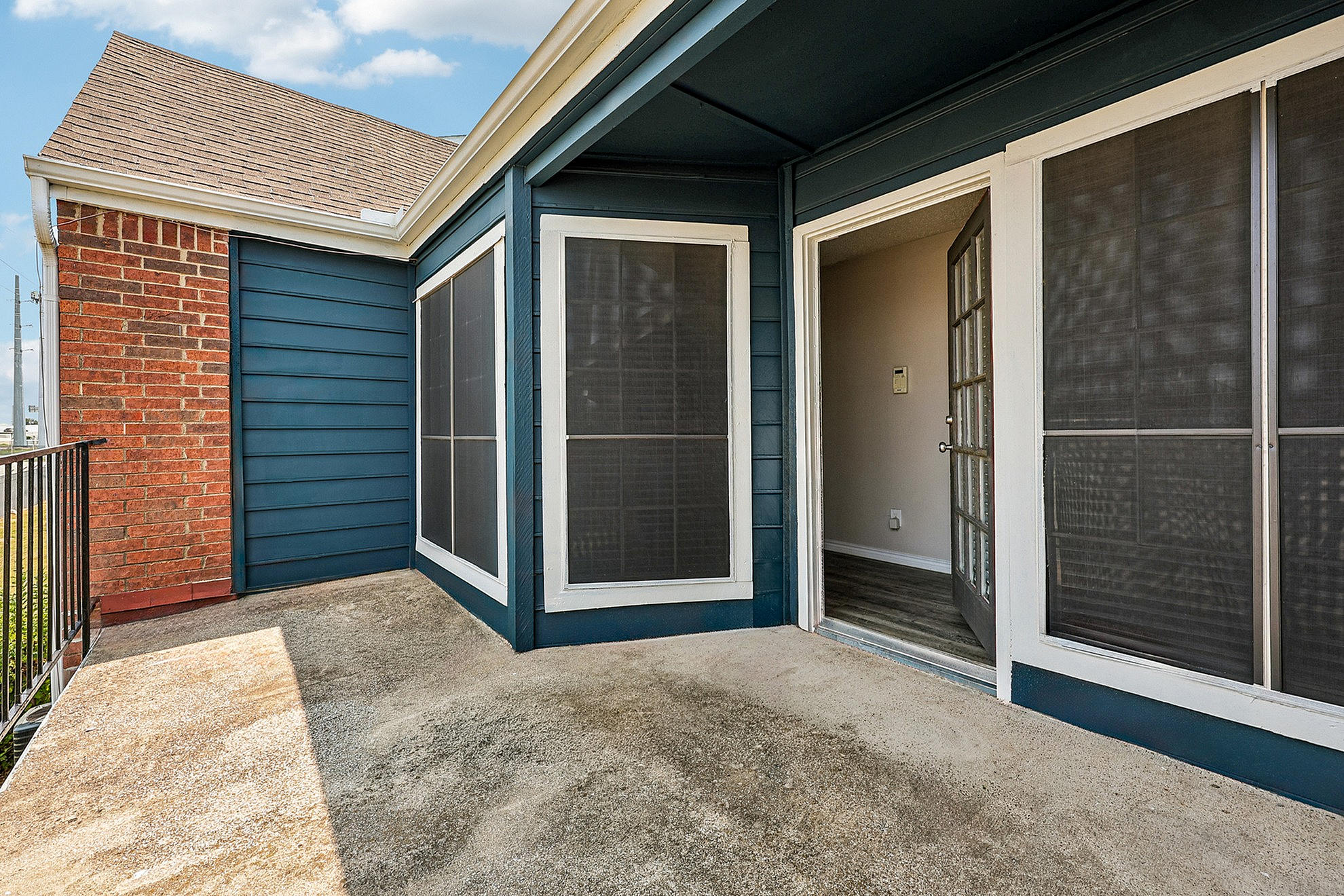 Charming outdoor patio space with brick and navy siding, ideal for relaxing and enjoying sunny days.