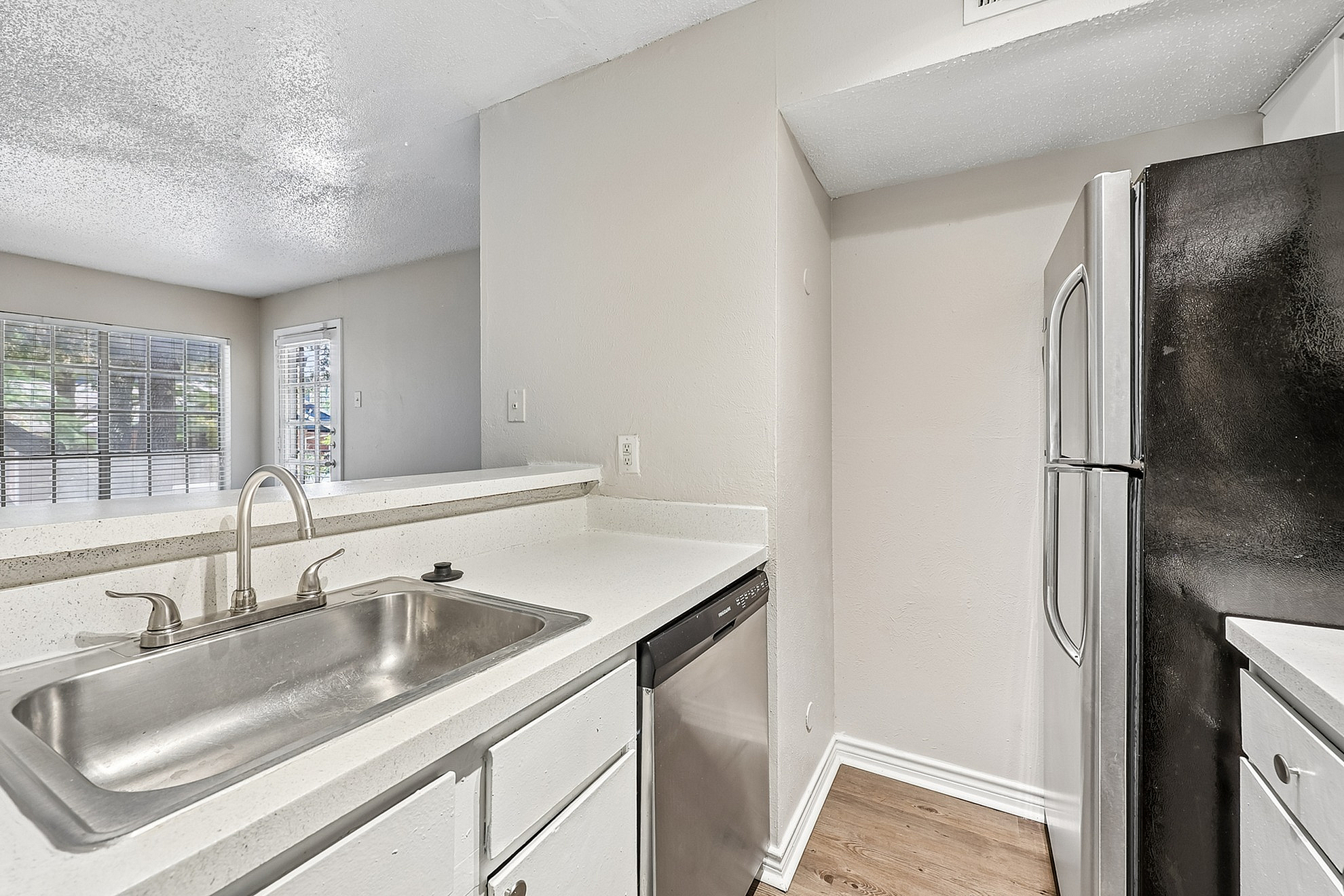 Bright and modern kitchen with sleek countertops, stainless steel sink, and ample natural light from large windows.
