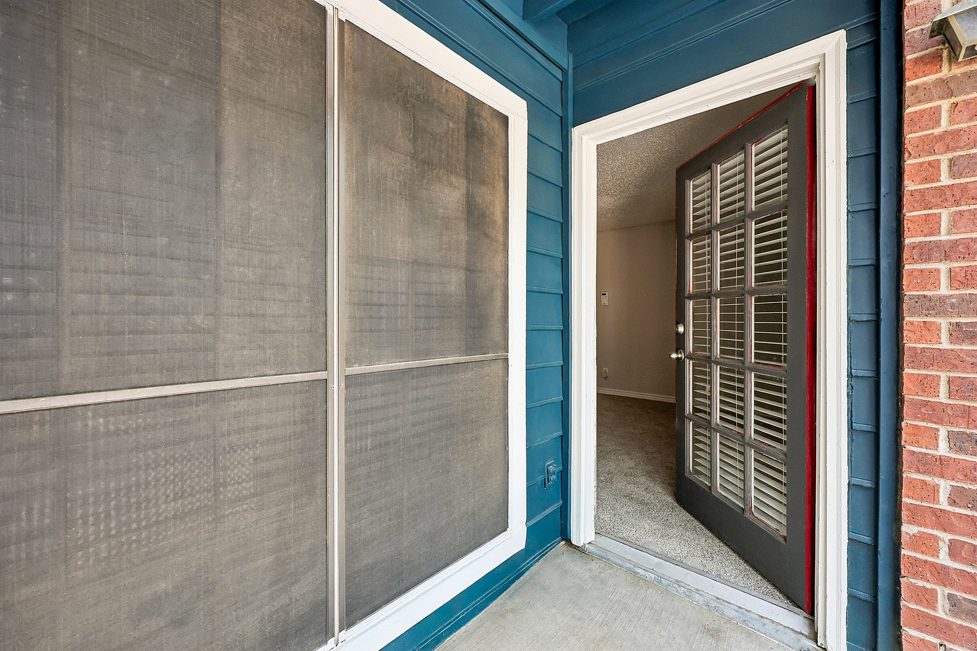 Charming apartment entryway with blue siding and an inviting open door, perfect for welcoming guests.