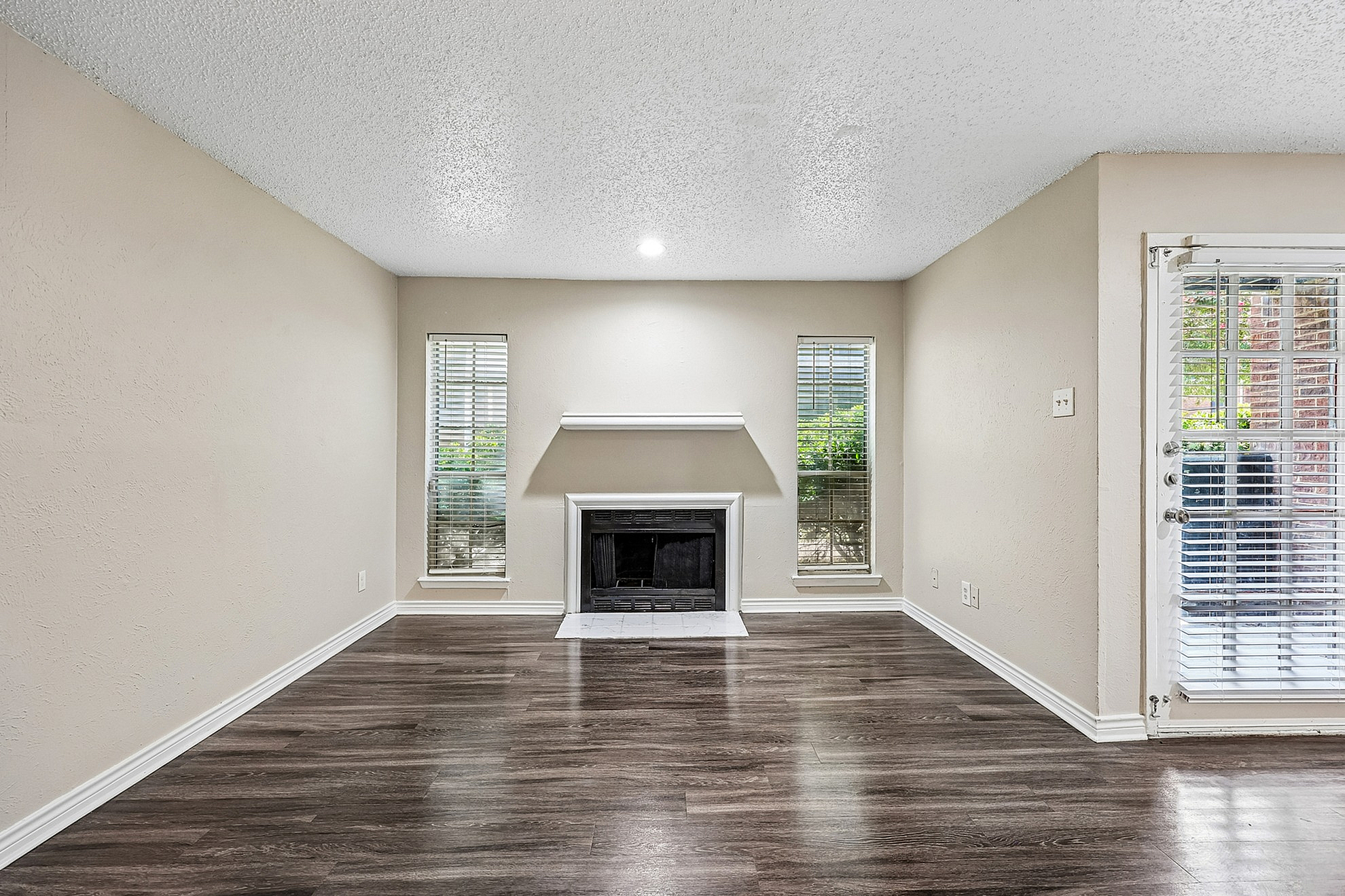 Elegant living room featuring a cozy fireplace, chic hardwood floors, and ample natural light from large windows.