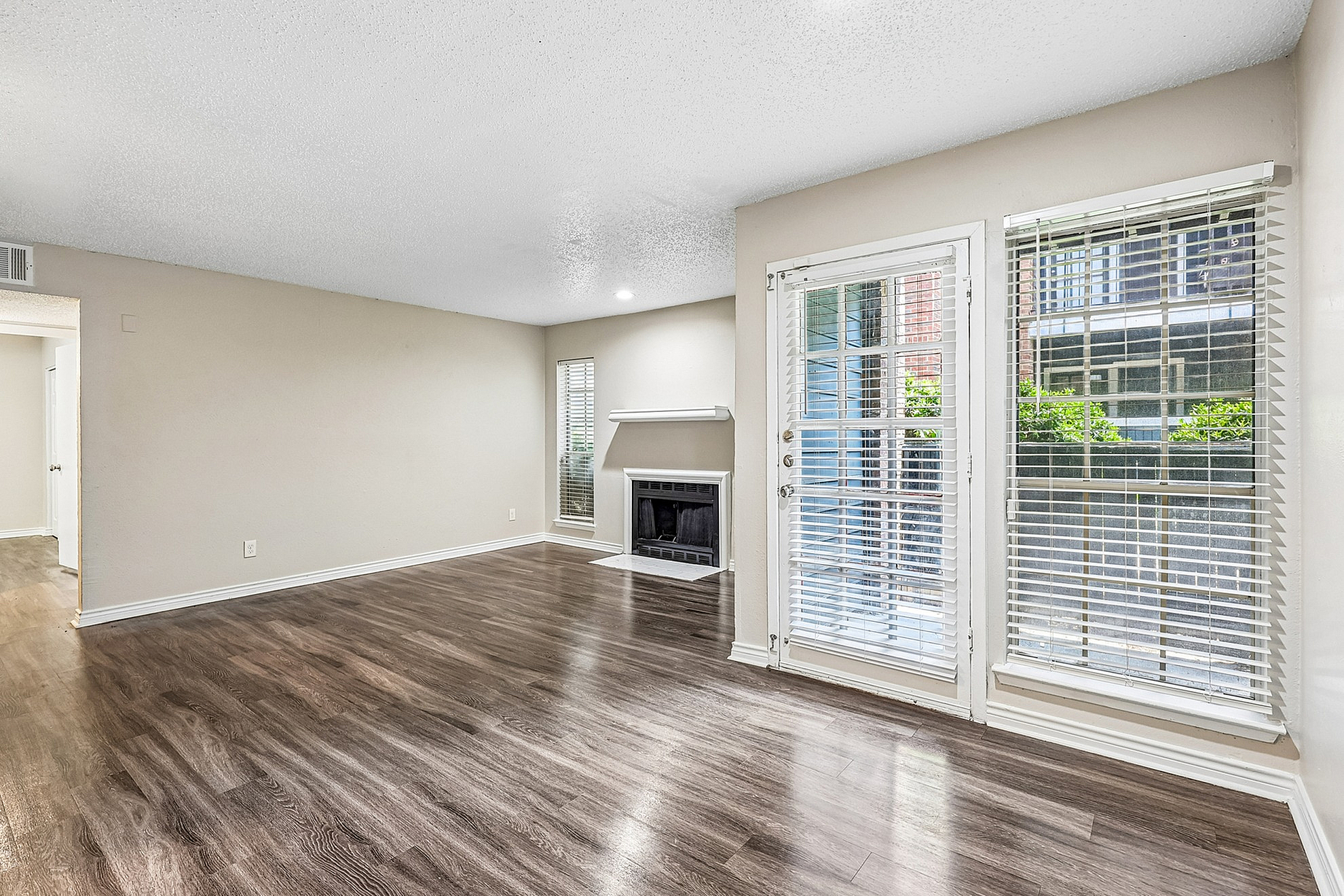 Bright and airy living room featuring elegant hardwood floors, a cozy fireplace, and large windows with abundant natural light.