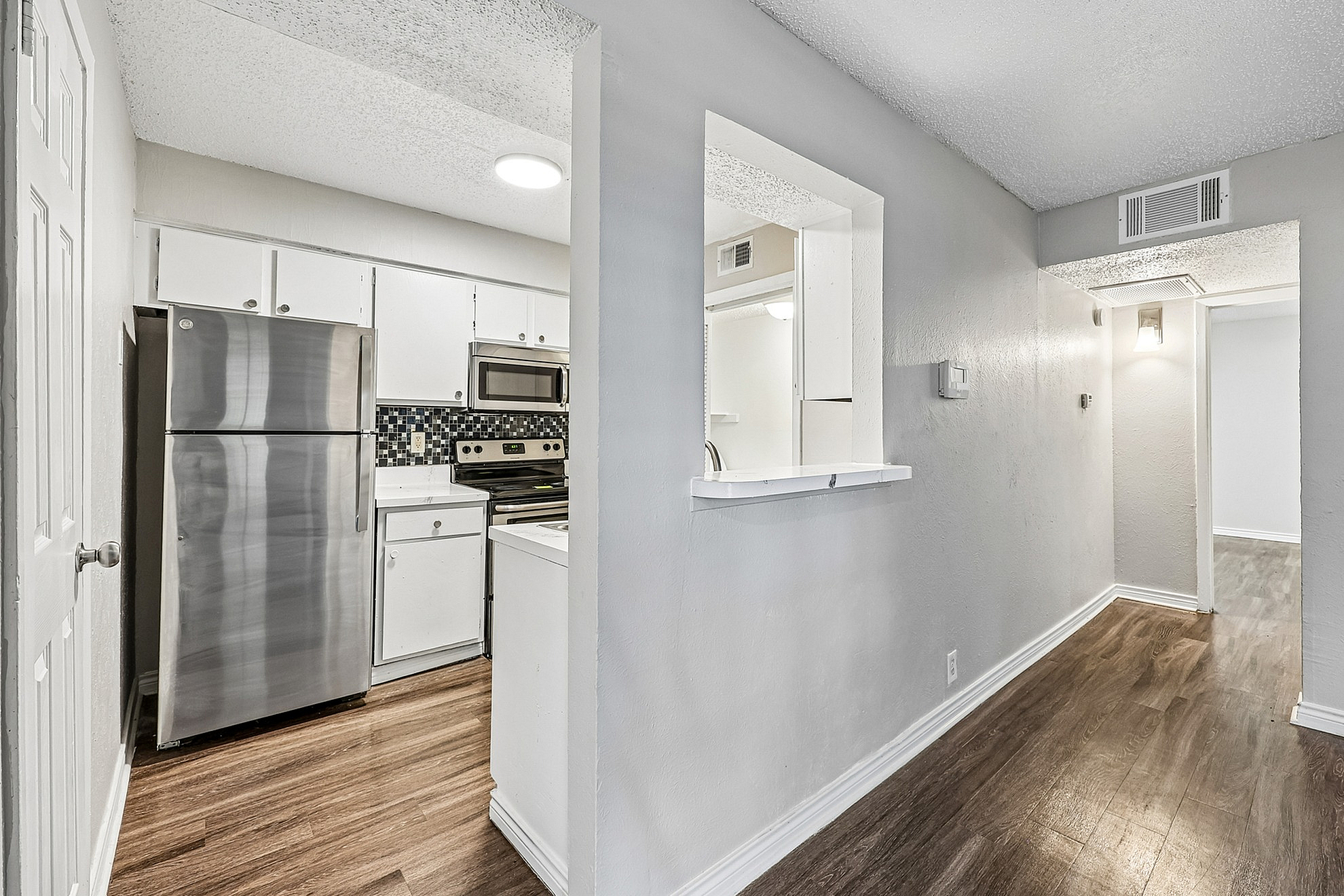 Modern kitchen with sleek stainless steel appliances, chic backsplash, and elegant wood flooring in a bright, inviting space.