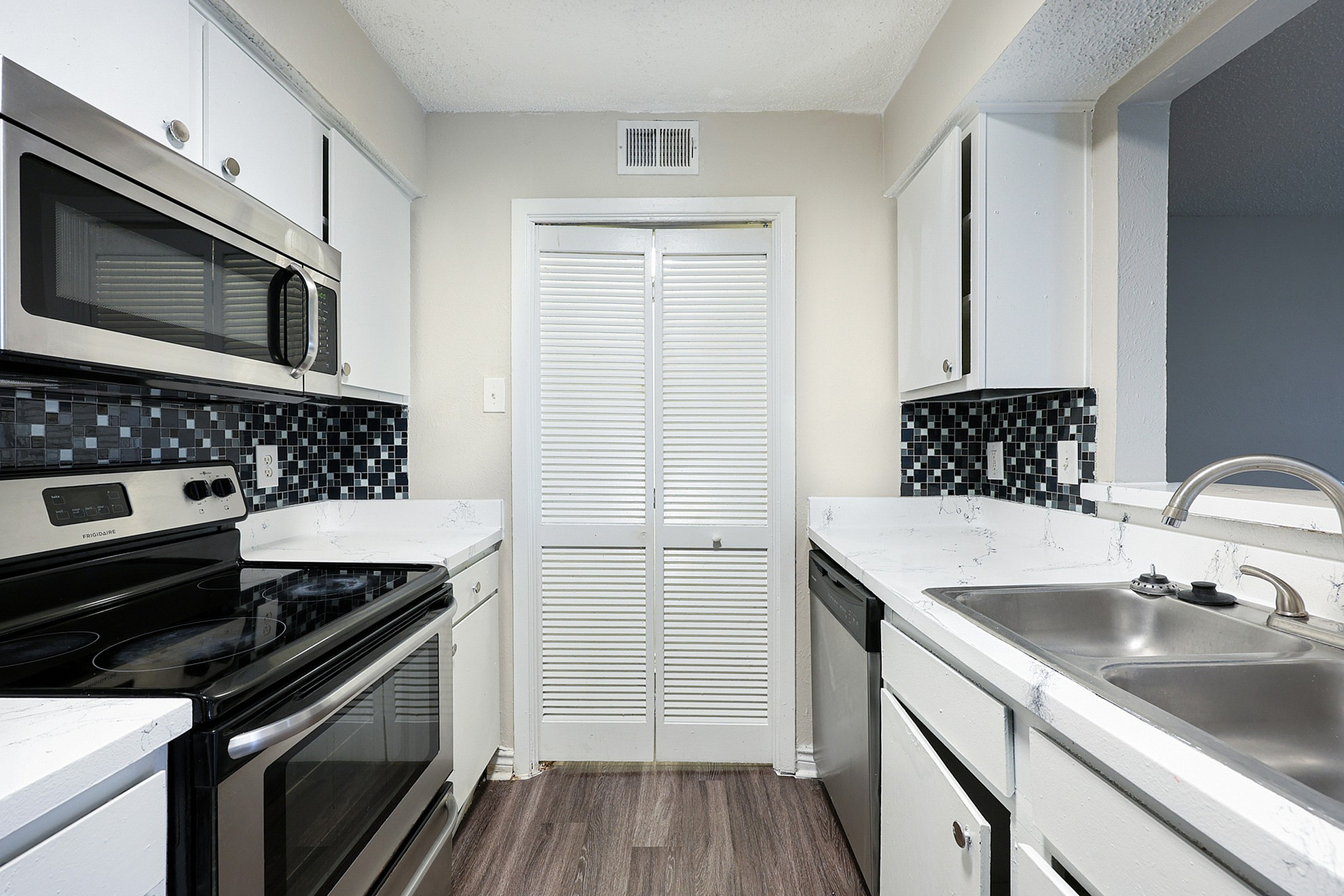 Modern kitchen with sleek stainless steel appliances, chic black and white tiled backsplash, and elegant countertops.