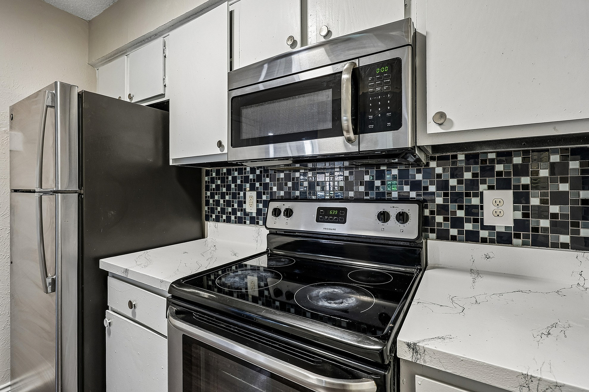 Modern kitchen with sleek stainless steel appliances, patterned backsplash, and elegant marble countertops.
