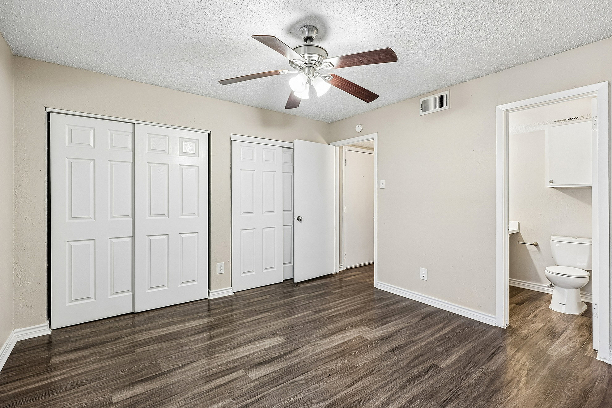 Charming bedroom with elegant wooden floors, a ceiling fan, and convenient en-suite bathroom access.