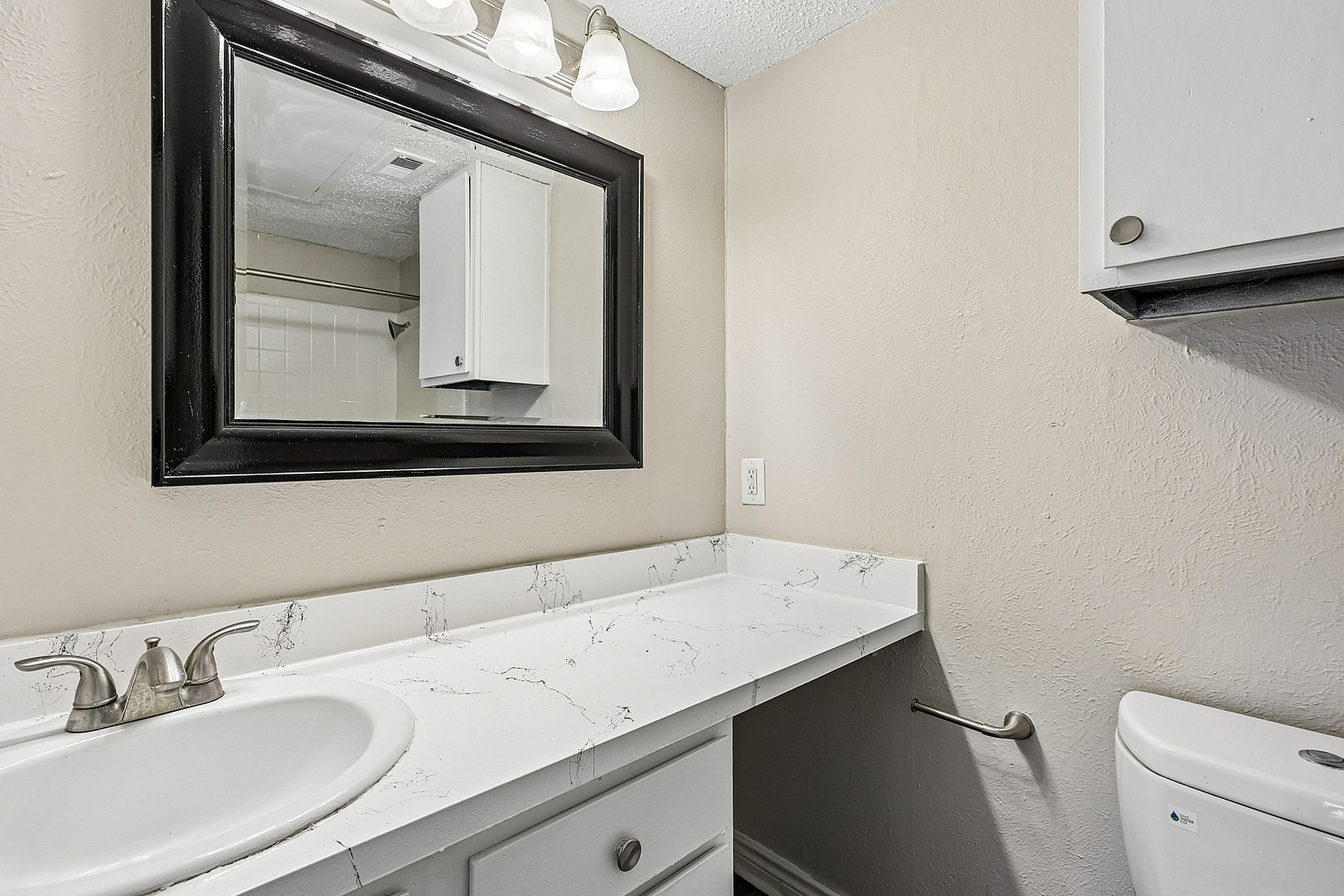 Elegant bathroom with a sleek vanity, modern mirror, and pristine white countertop.