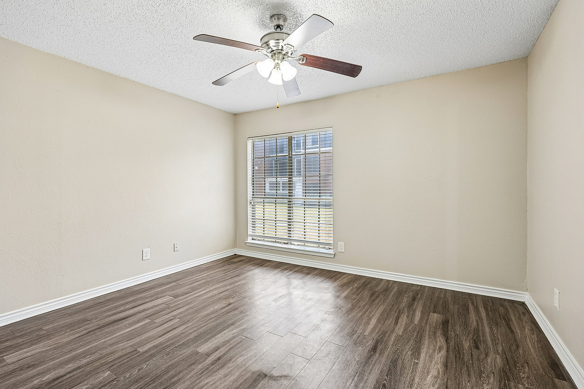 Bright, inviting room with elegant wood flooring and a modern ceiling fan, perfect for relaxation.