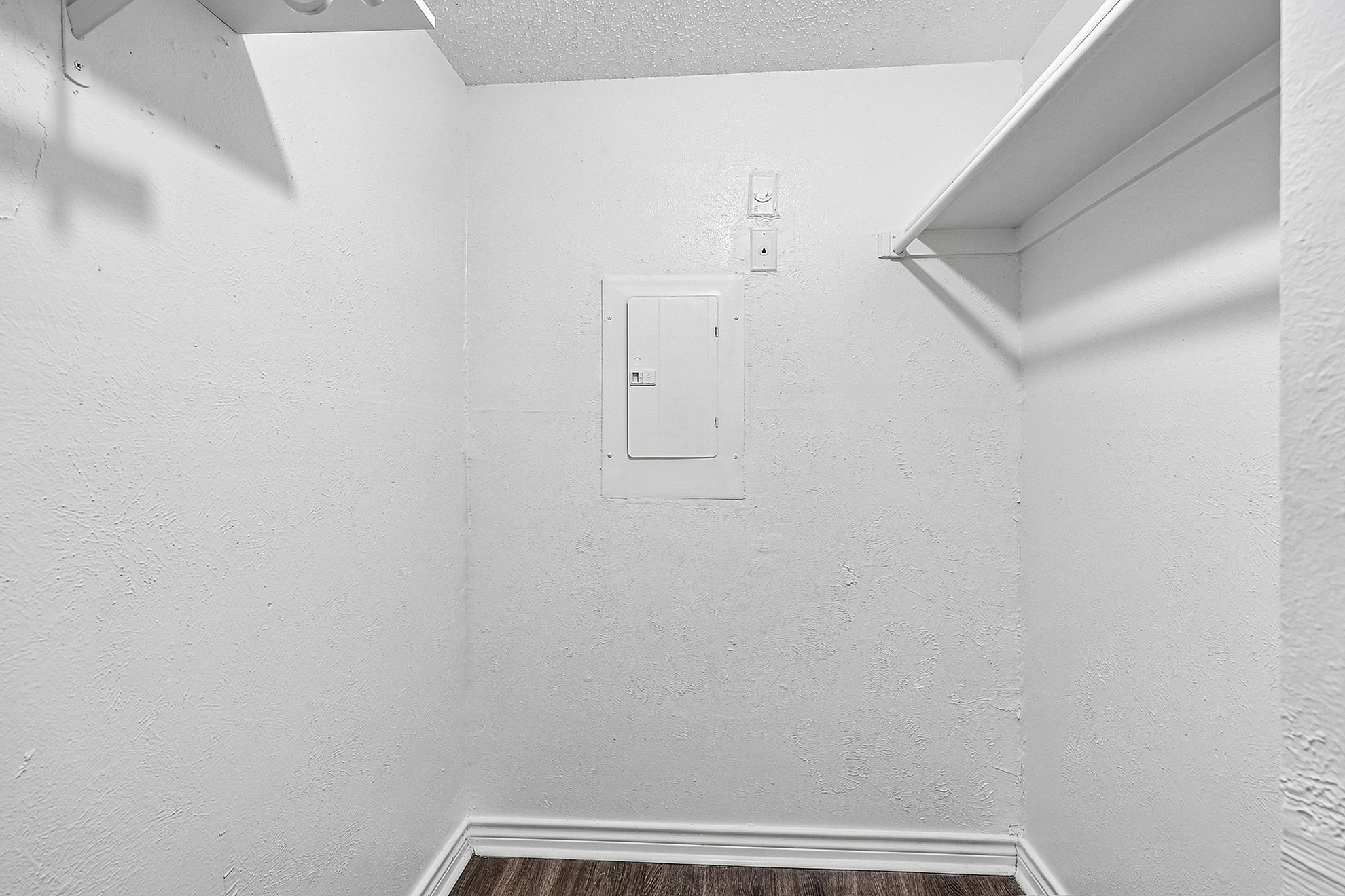Cozy walk-in closet with ample shelving and sleek hardwood flooring, perfect for organized storage.