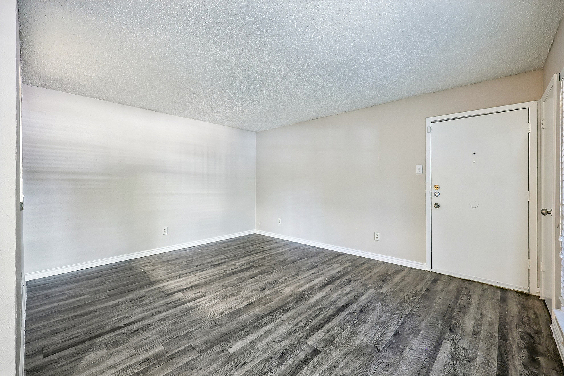 Spacious and bright living area with elegant wood flooring and neutral tones, offering a warm and inviting ambiance.