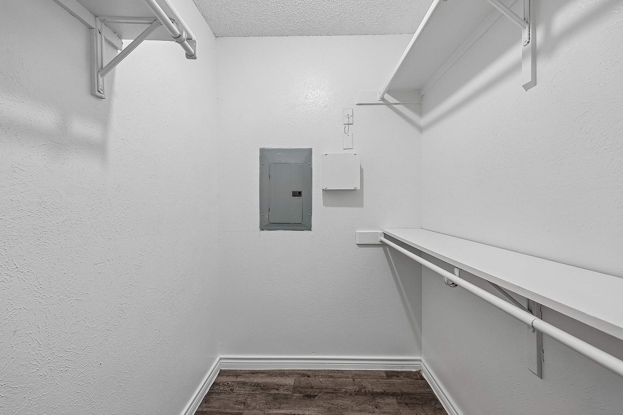 Spacious walk-in closet with ample shelving and hanging space, featuring elegant wood flooring and practical storage design.