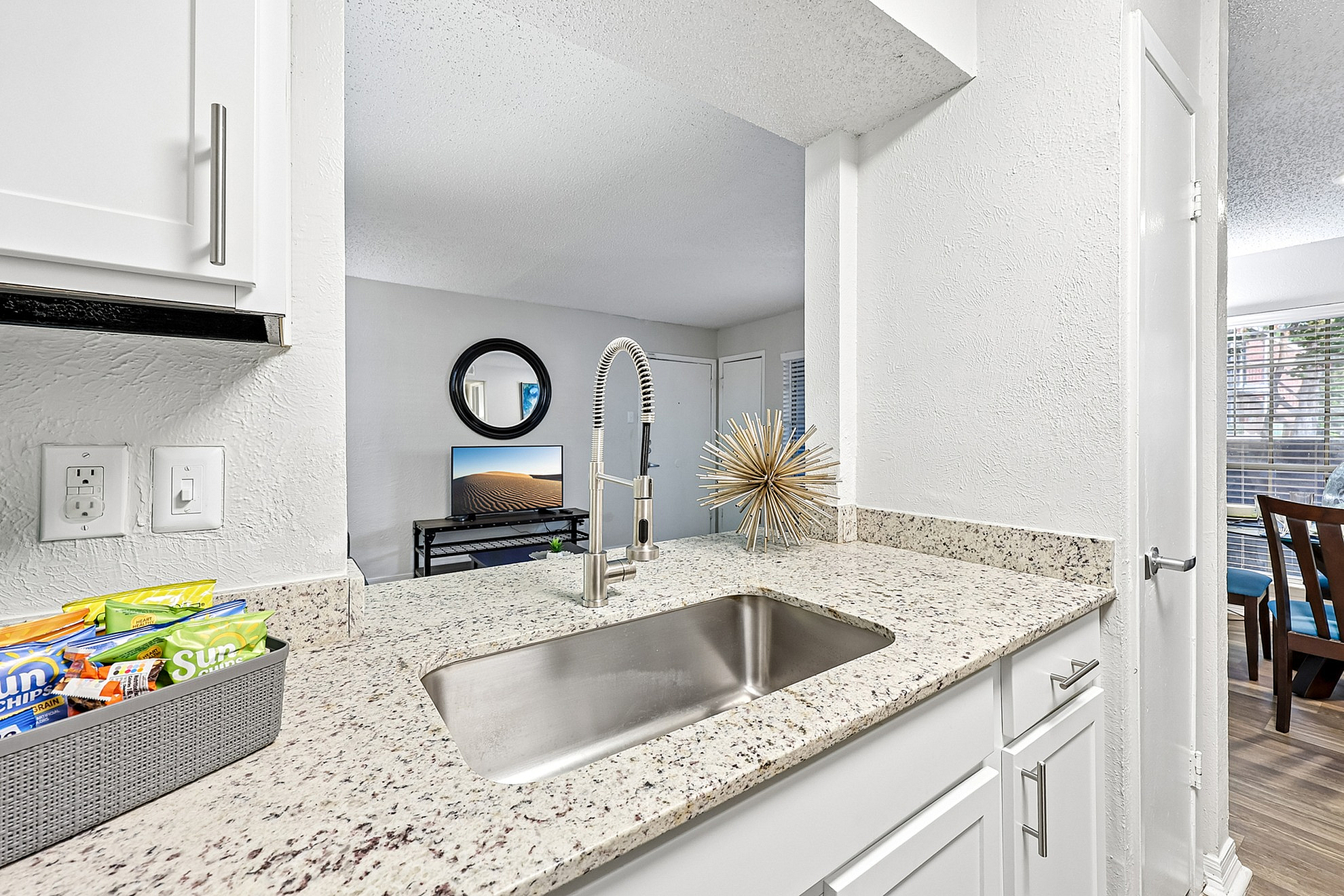 Modern kitchen view with sleek granite countertops and stylish fixtures overlooking a cozy living area.