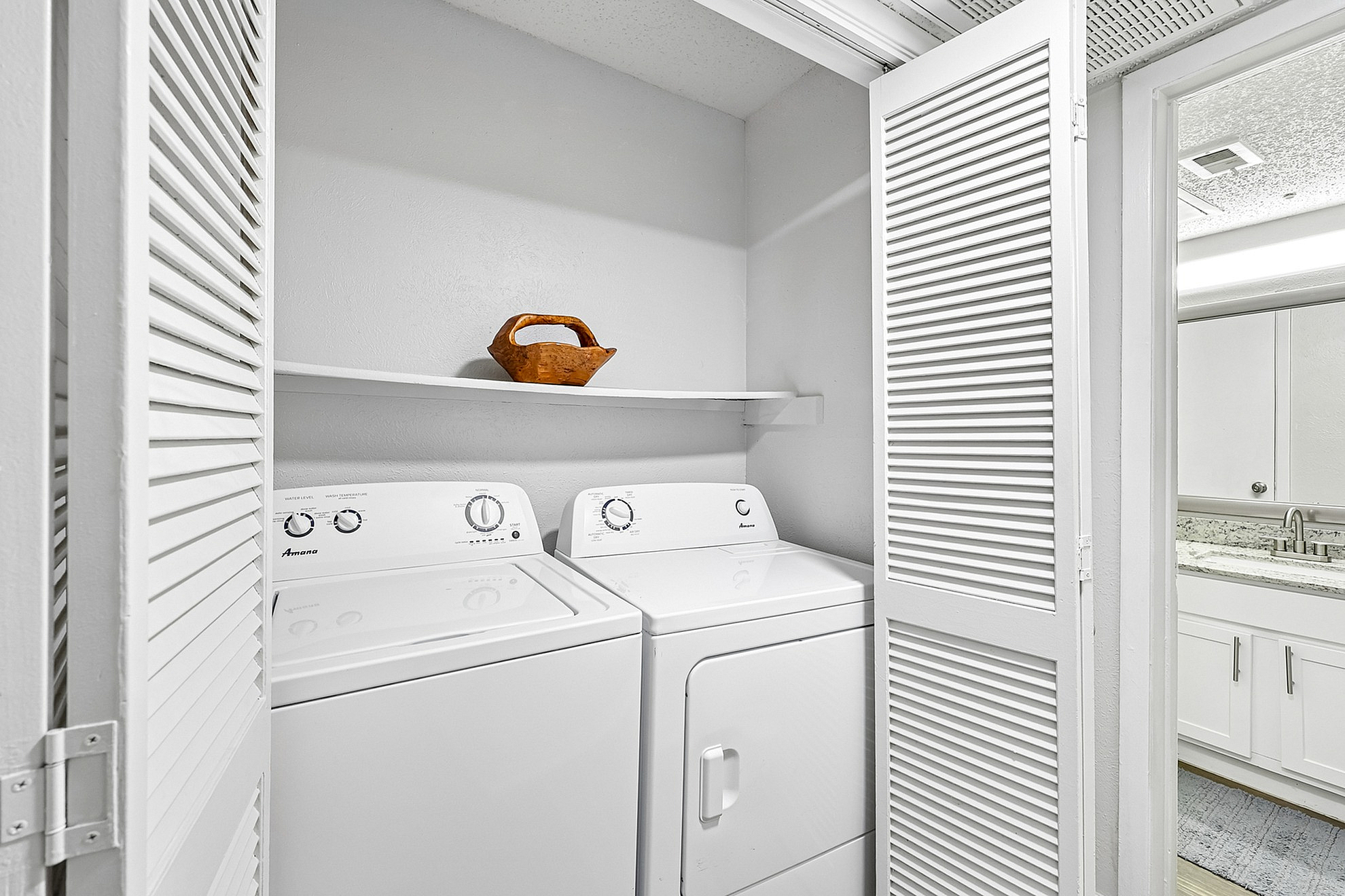 Chic laundry nook with modern washer and dryer, featuring sleek white cabinetry and a stylish wicker basket accent.