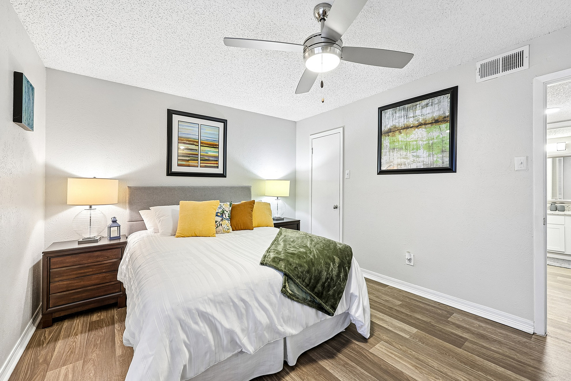 Cozy bedroom with modern decor, wood flooring, and contemporary art, perfect for relaxation.
