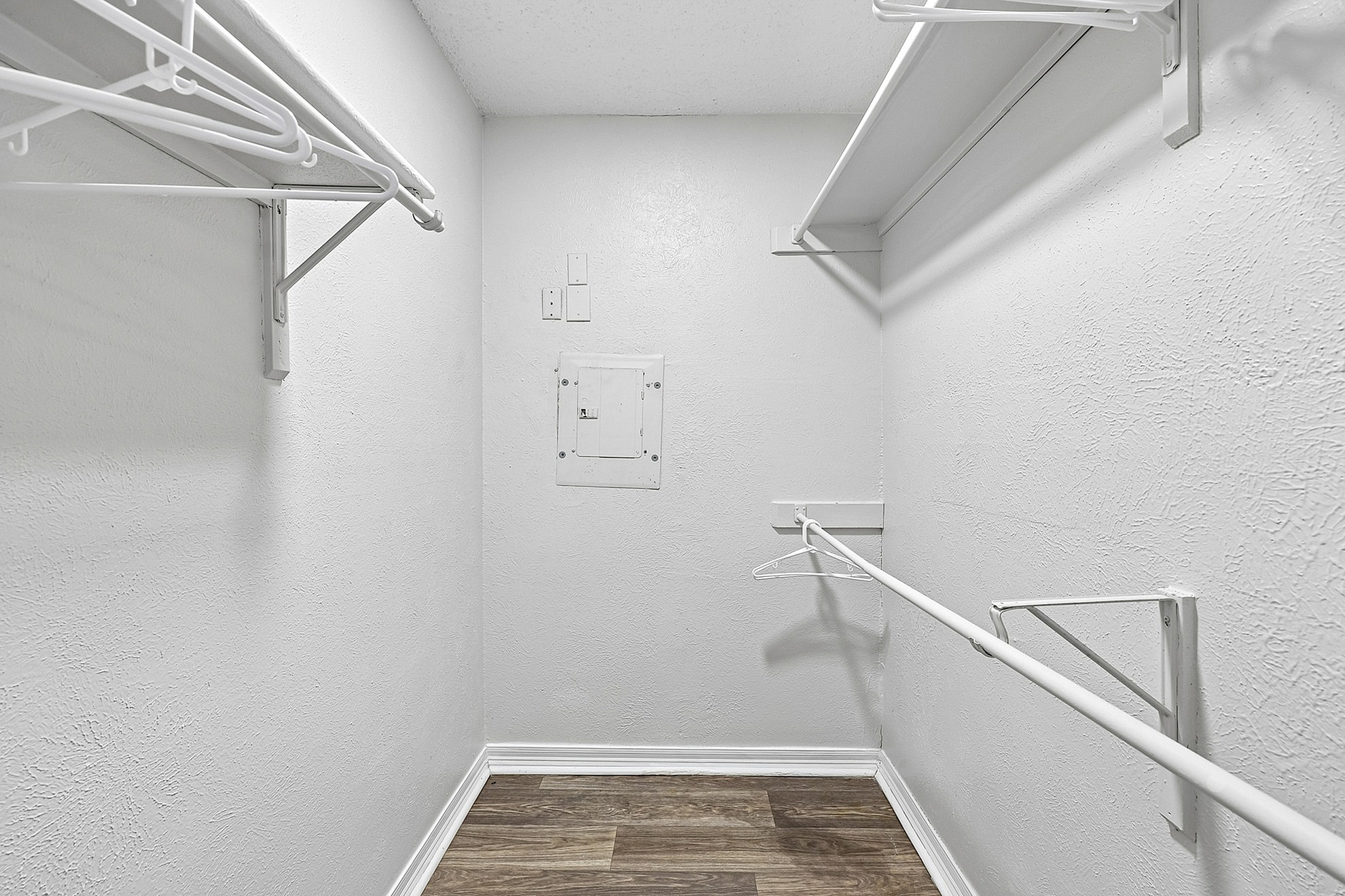 Spacious walk-in closet with sleek white shelving and ample hanging space, perfect for organizing a stylish wardrobe.