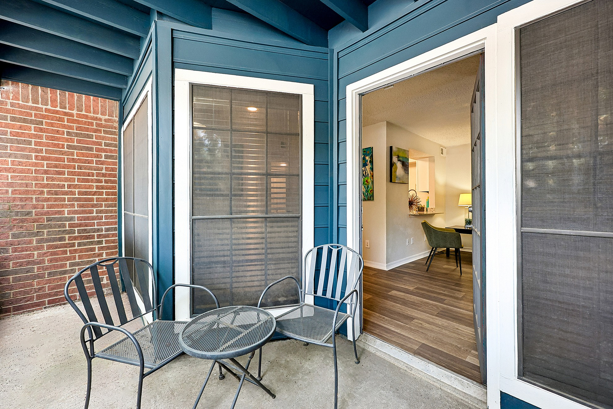 Charming apartment balcony with cozy seating, leading into a warmly lit living area with modern decor.