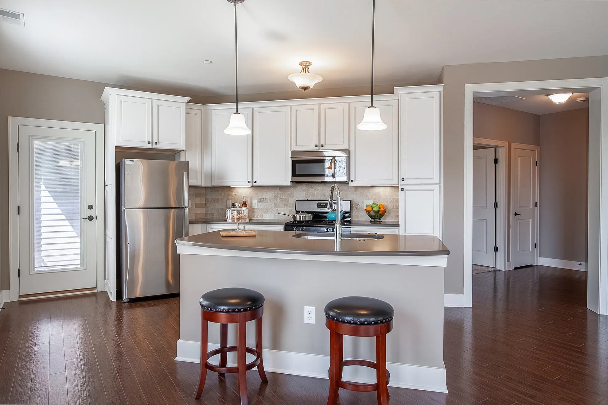 Modern kitchen with stainless steel appliances, elegant pendant lighting, and a spacious island with seating.