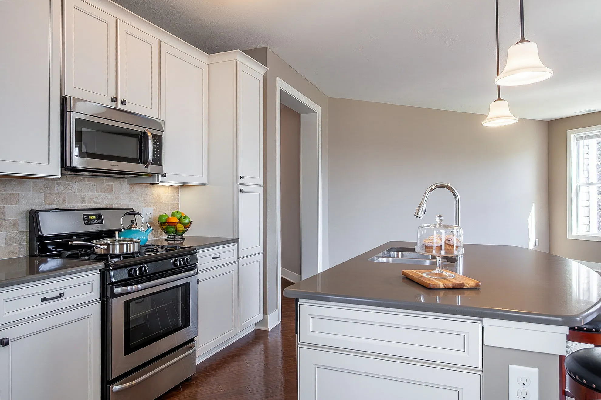 Modern kitchen with sleek stainless steel appliances, elegant white cabinetry, and a polished island with integrated sink and stylish pendant lighting.