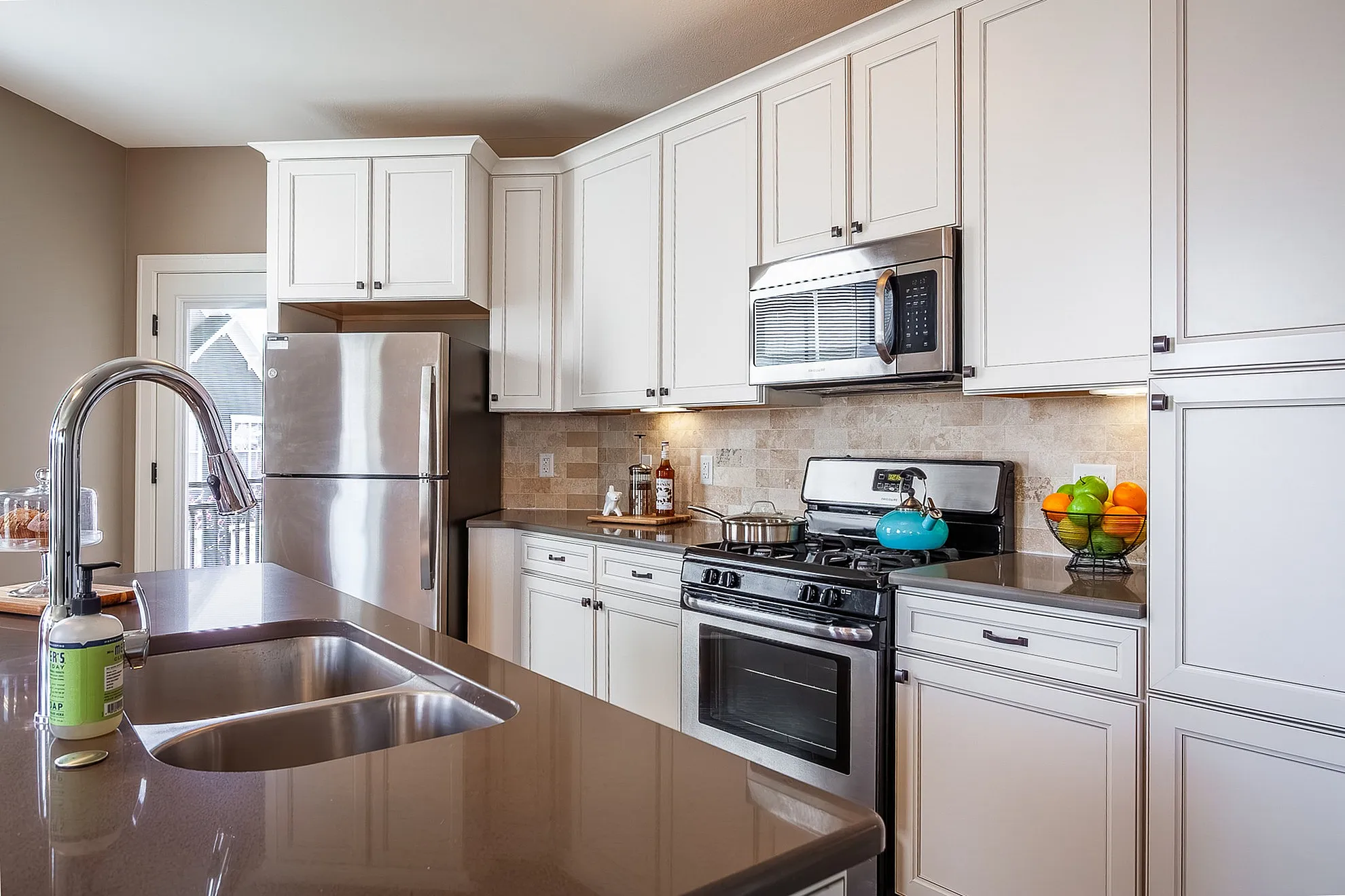 Modern kitchen with sleek stainless steel appliances, chic cabinetry, and elegant stone countertops.