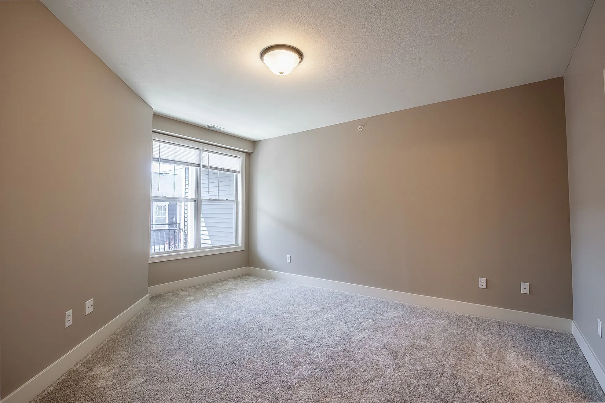 Bright, spacious bedroom with plush carpet and large window allowing natural light to flood the room.