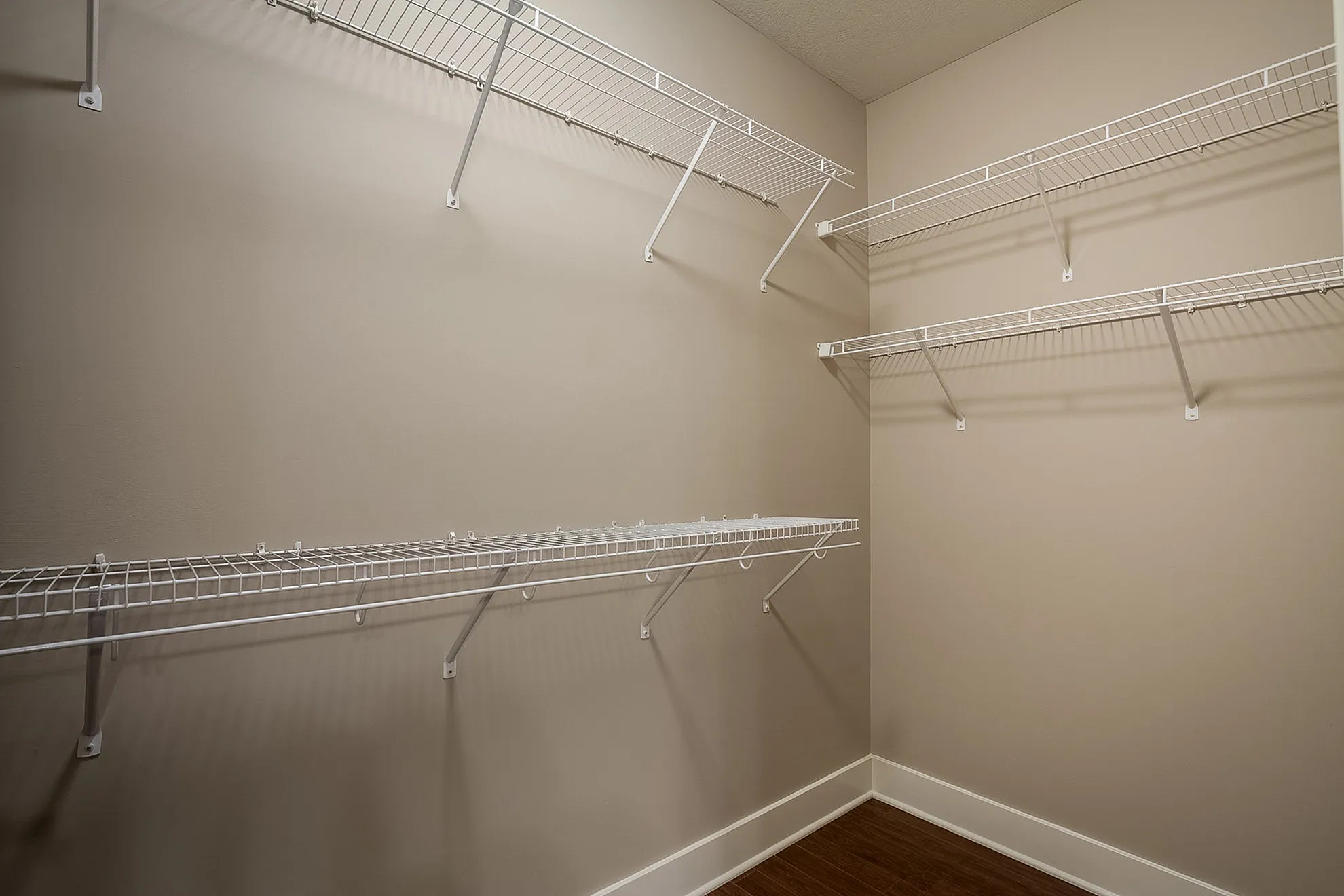 Spacious walk-in closet with modern wire shelving and elegant hardwood flooring.