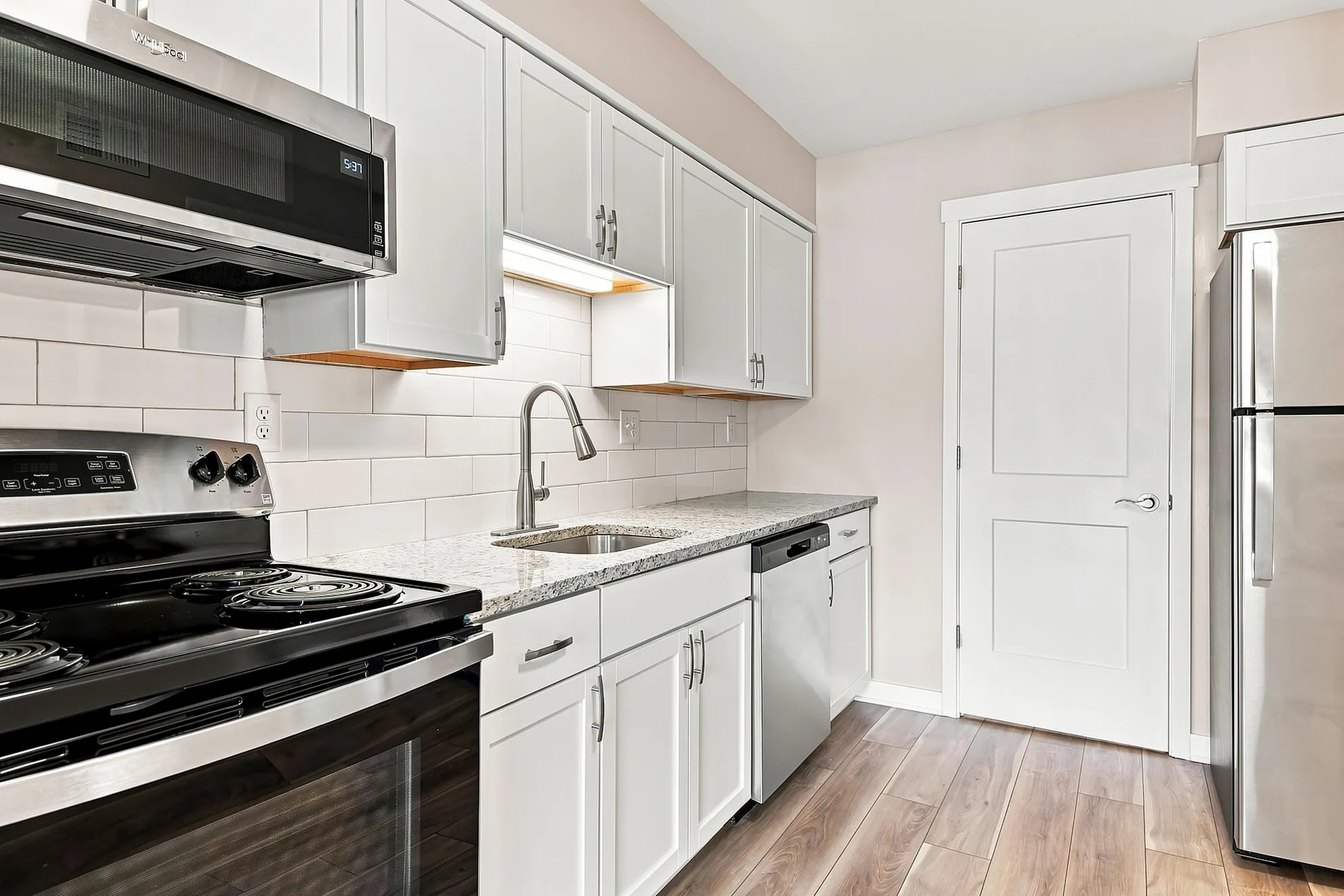 Elegant modern kitchen with sleek stainless steel appliances, granite countertops, and chic white cabinetry.
