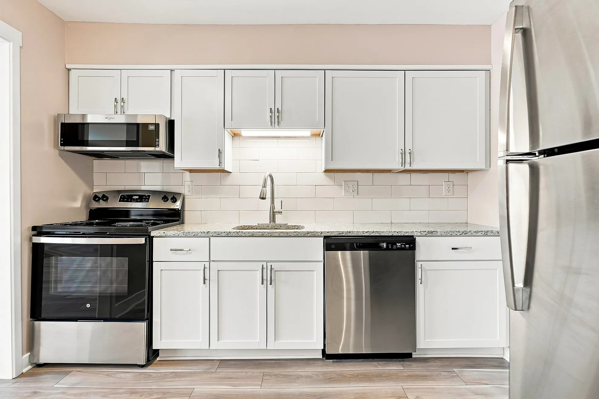 Modern kitchen with sleek stainless steel appliances, elegant white cabinetry, and a stylish tile backsplash.