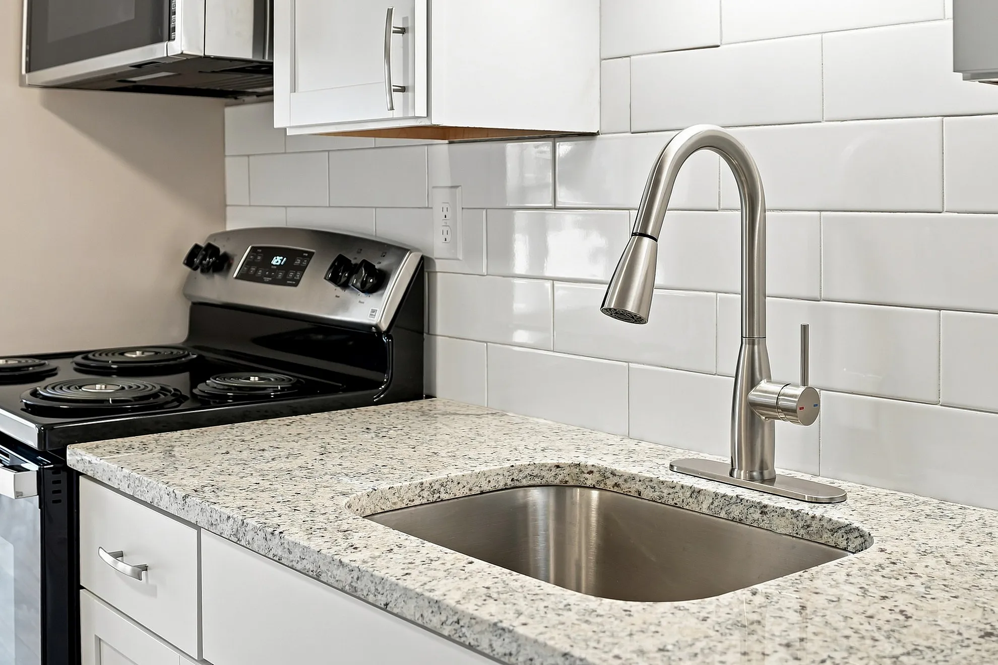 Modern kitchen with sleek stainless steel appliances, elegant granite countertops, and a stylish subway tile backsplash.