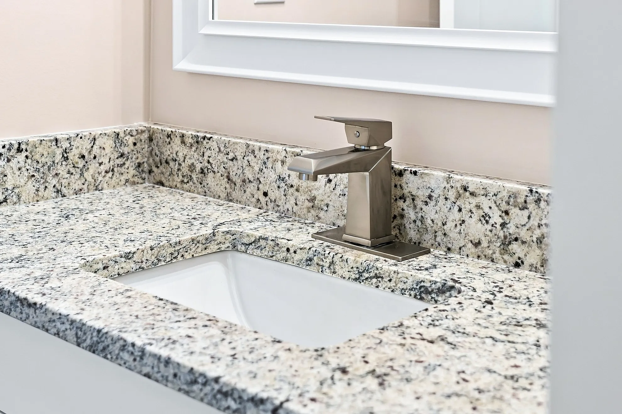 Elegant bathroom vanity with polished granite countertop and modern chrome faucet, offering a touch of luxury and style.