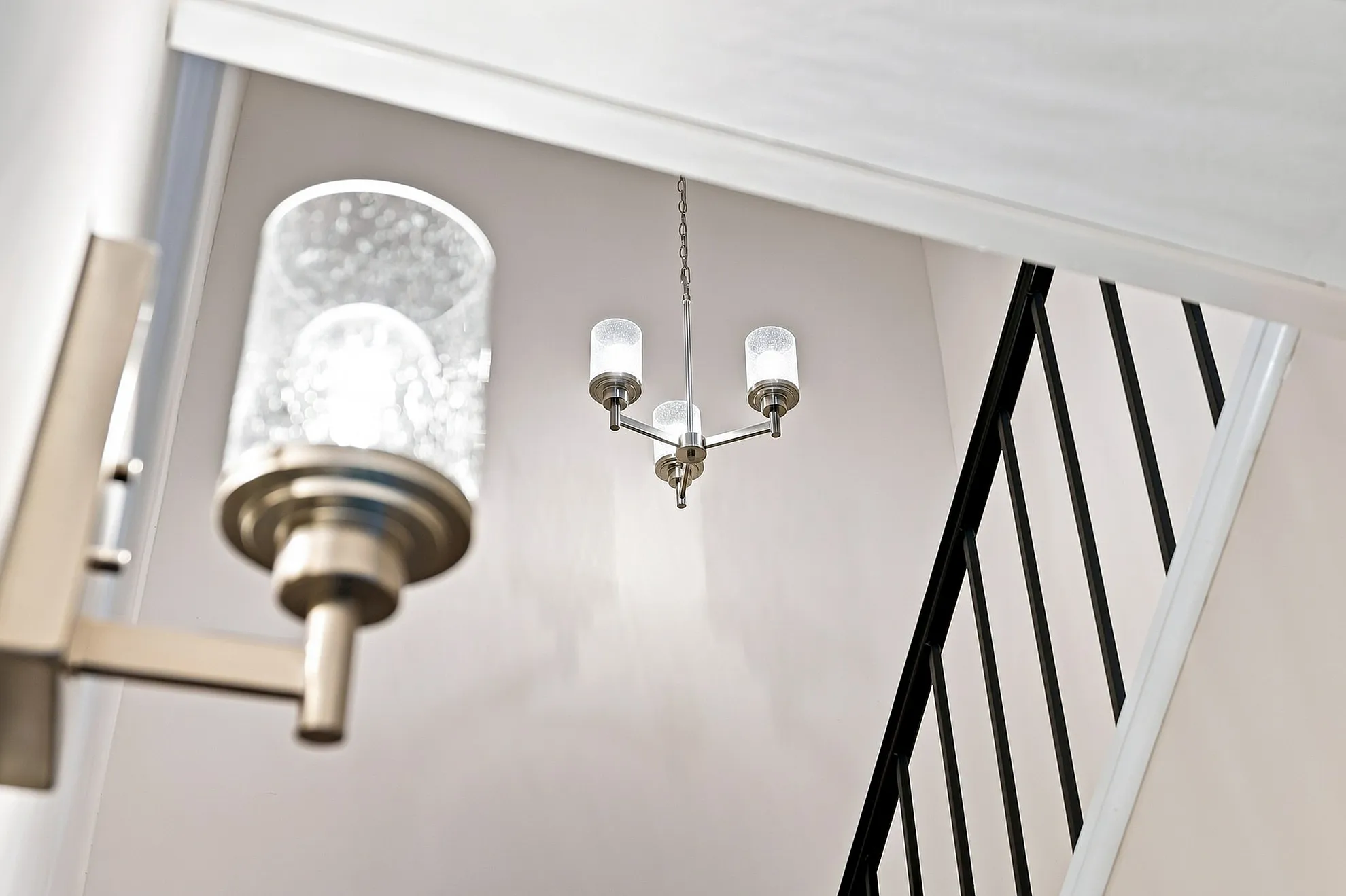 Modern apartment hallway with elegant lighting fixtures and sleek black stair railings.