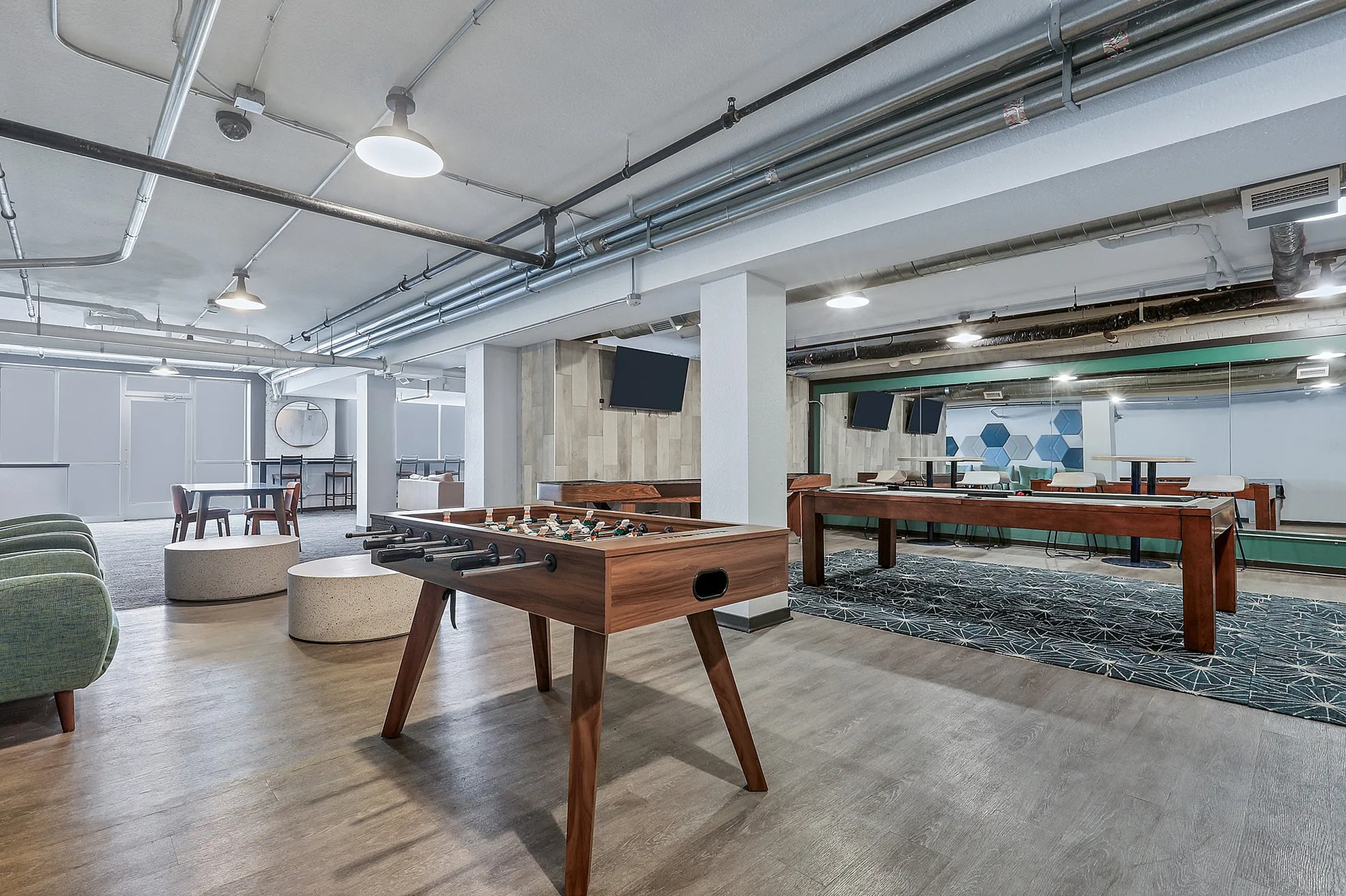 Modern recreational lounge with stylish foosball and shuffleboard tables, cozy seating, and chic decor.