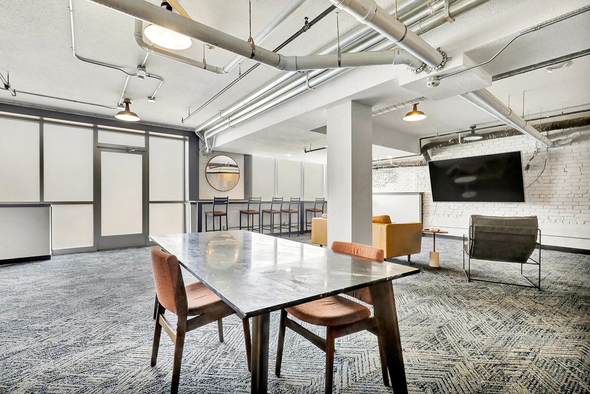 Contemporary open-concept living space with stylish exposed ducts, modern dining area, and cozy seating with a large wall-mounted TV.
