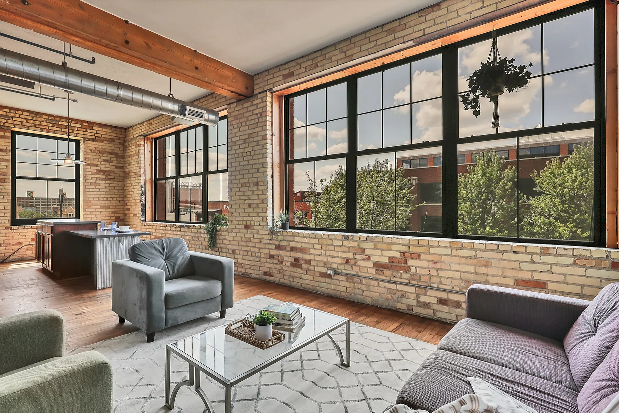 Charming loft apartment with exposed brick walls, large windows offering abundant natural light, and an inviting open living space.