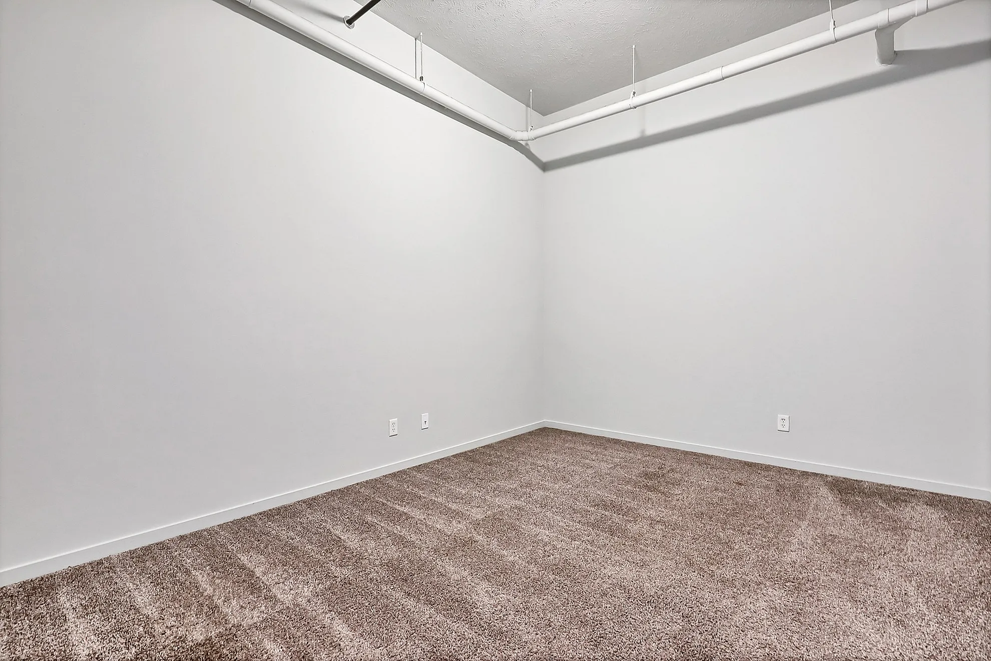 Bright and spacious room with modern ceiling fixtures and plush carpet, perfect for versatile living options.