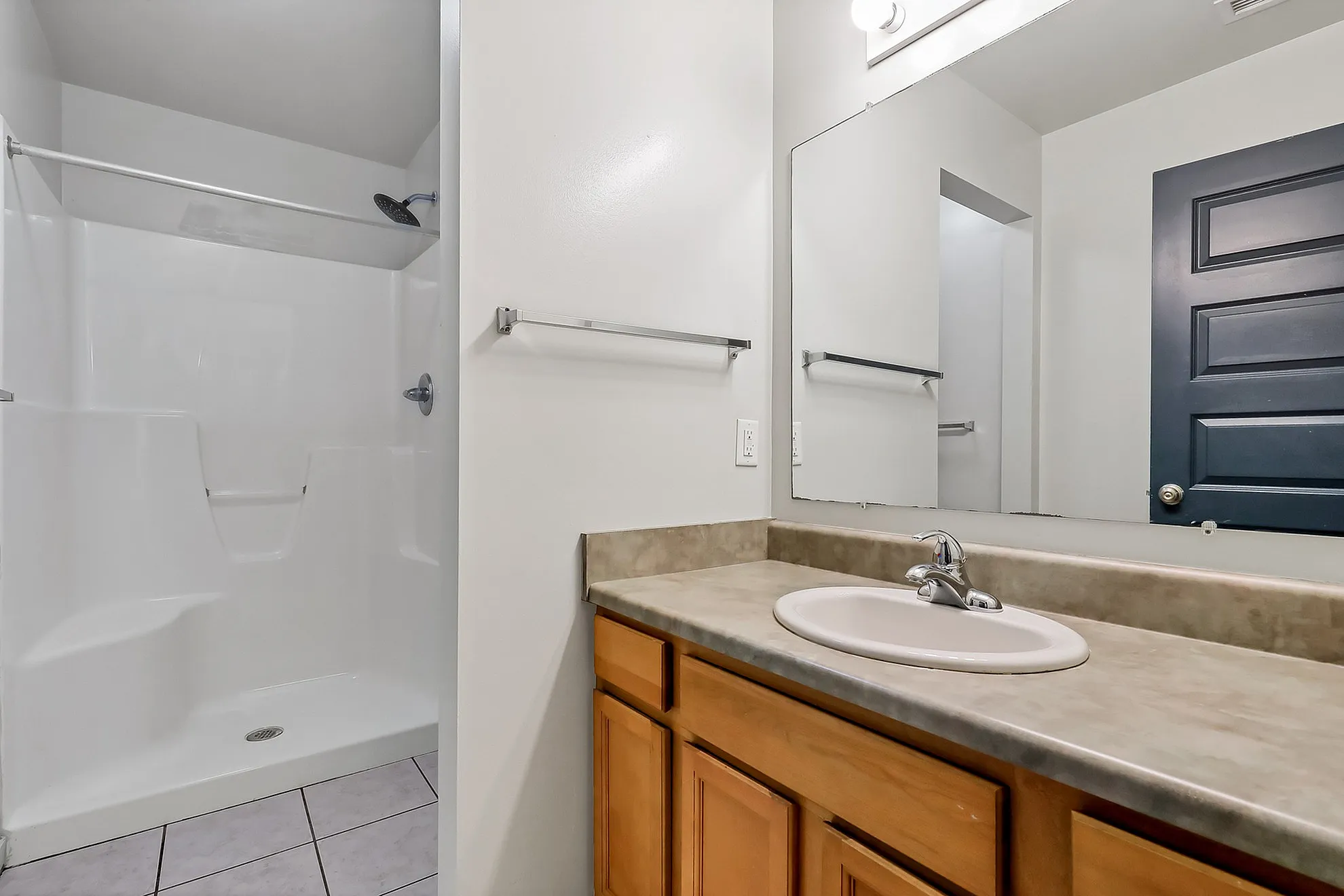 Modern bathroom featuring a sleek shower, spacious vanity, and large mirror.