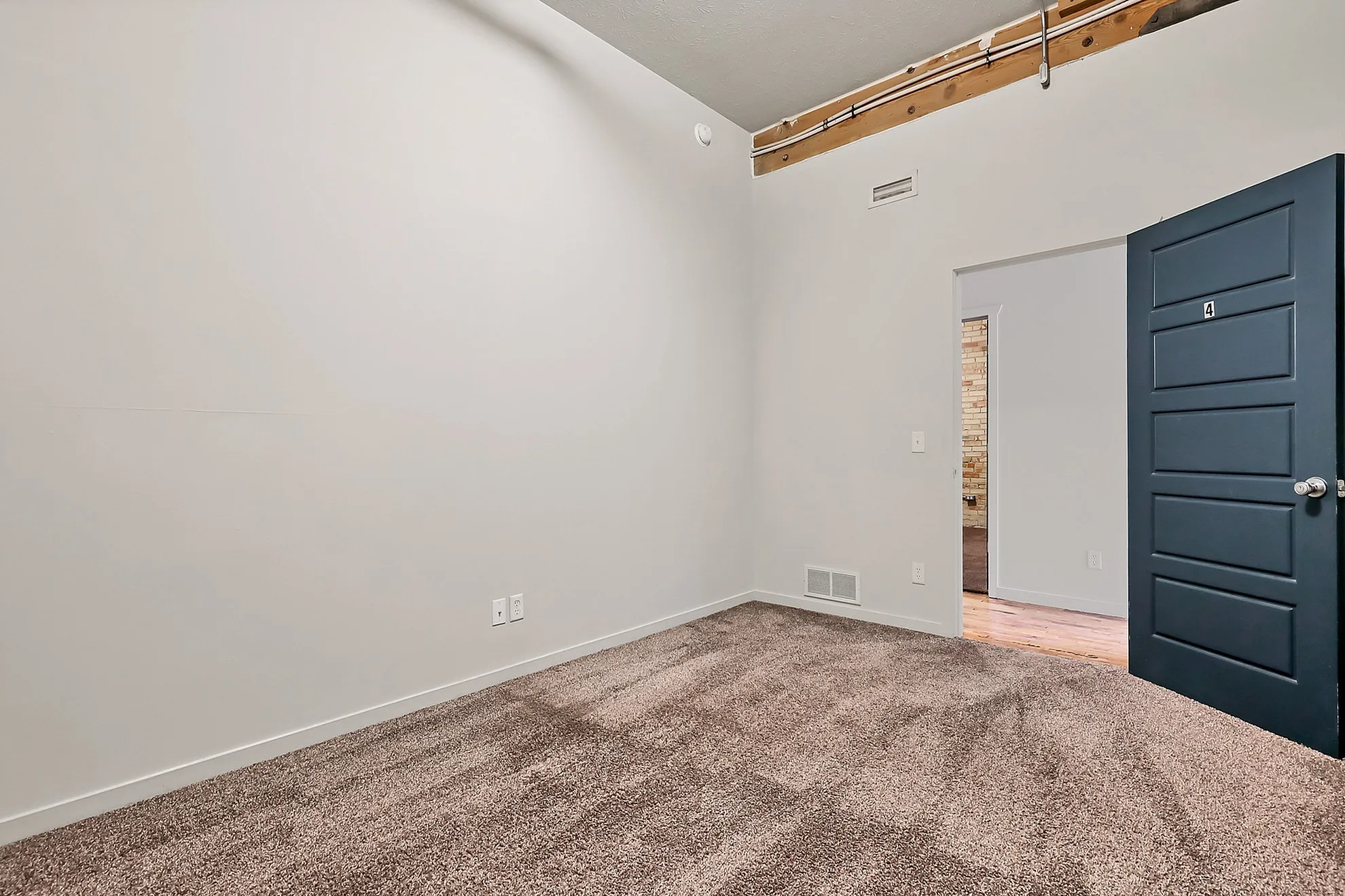 Contemporary bedroom with plush carpet flooring and sleek black door, offering a cozy and modern aesthetic.