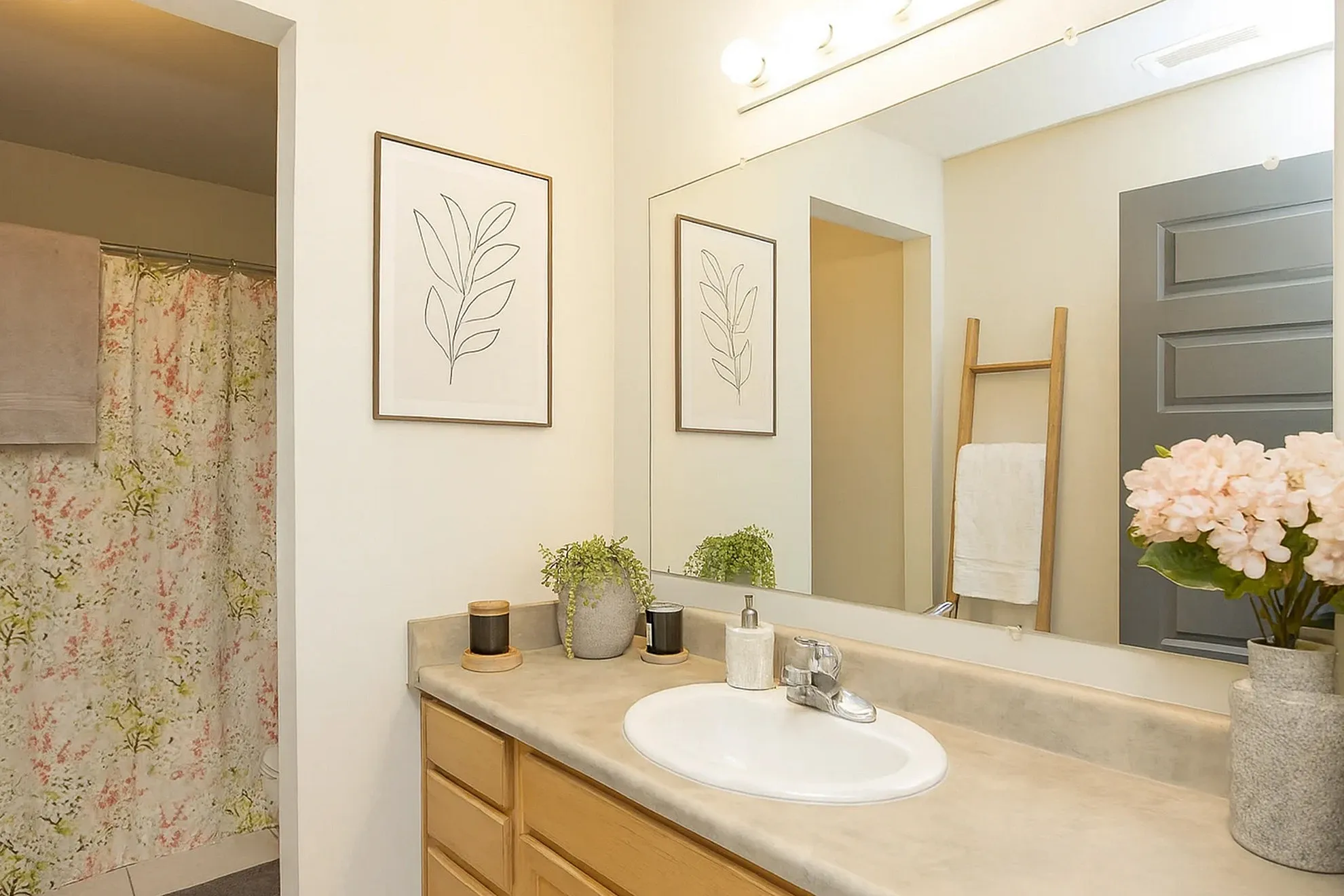 Bright and inviting bathroom with modern amenities, elegant floral decor, and a stylish vanity mirror.